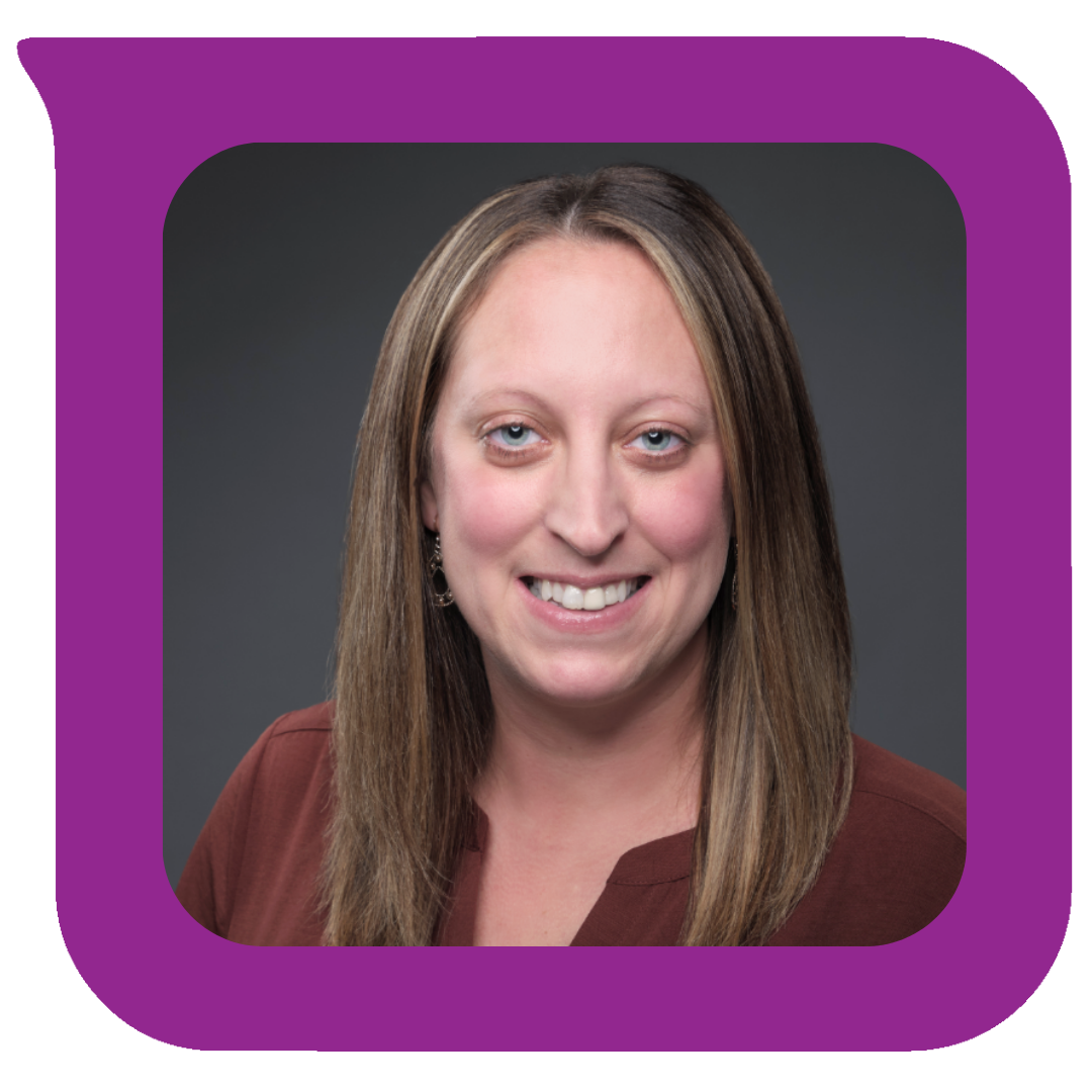 ဆံပင်ရှည် အညိုရောင်၊ မျက်လုံးပြာပြာနှင့် အပြုံးကြီးကြီးဖြင့် အမျိုးသမီးတစ်ဦးသည် အညိုရောင်အင်္ကျီကို ဝတ်ဆင်ထားပြီး ရိုးရိုးမီးခိုးရောင်နောက်ခံတွင် ပို့စ်ပေးနေသည်။