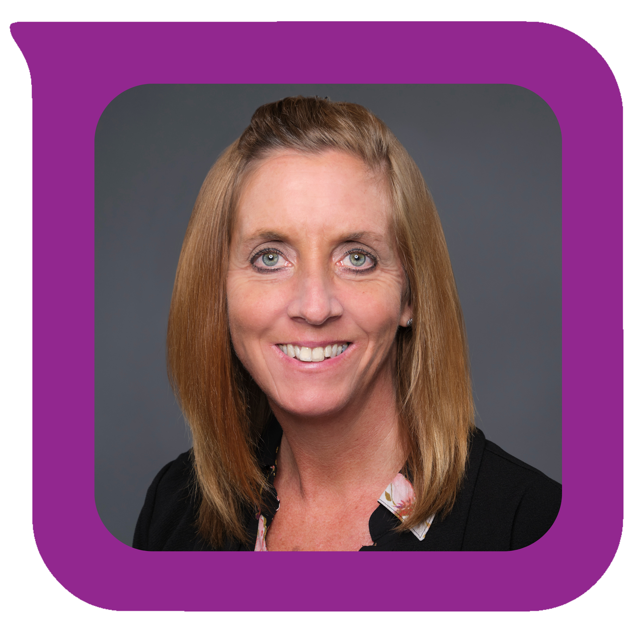 မီးခိုးရောင်နောက်ခံတွင် အနက်ရောင်ဘလေဇာအင်္ကျီနှင့် ပန်းပွင့်ဘလောက်စ်ကို ဝတ်ဆင်ထားသော ပခုံးအထိရှည်သော အနီရောင်ဆံပင်နှင့် ပြုံးရွှင်နေသော အမျိုးသမီးတစ်ဦး၏ ခေါင်းစီးဓာတ်ပုံ။