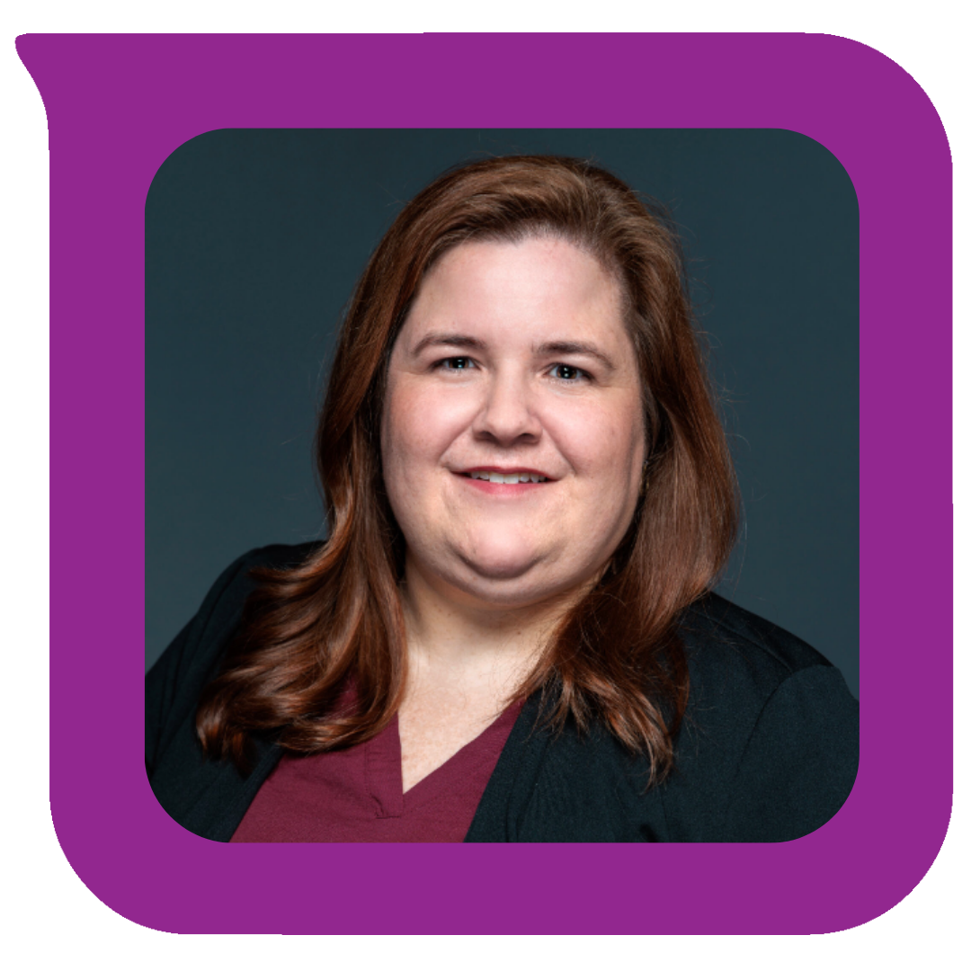 ပခုံးအထိရှည်သော အညိုရောင်ဆံပင်နှင့် ပြုံးရွှင်နေသော အမျိုးသမီးတစ်ဦး၏ ခေါင်းစီးဓာတ်ပုံ၊ မီးခိုးရောင်နောက်ခံတွင် နီရဲရဲအင်္ကျီပေါ်မှ အနက်ရောင်ဘလေဇာအင်္ကျီကို ဝတ်ဆင်ထားသည်။