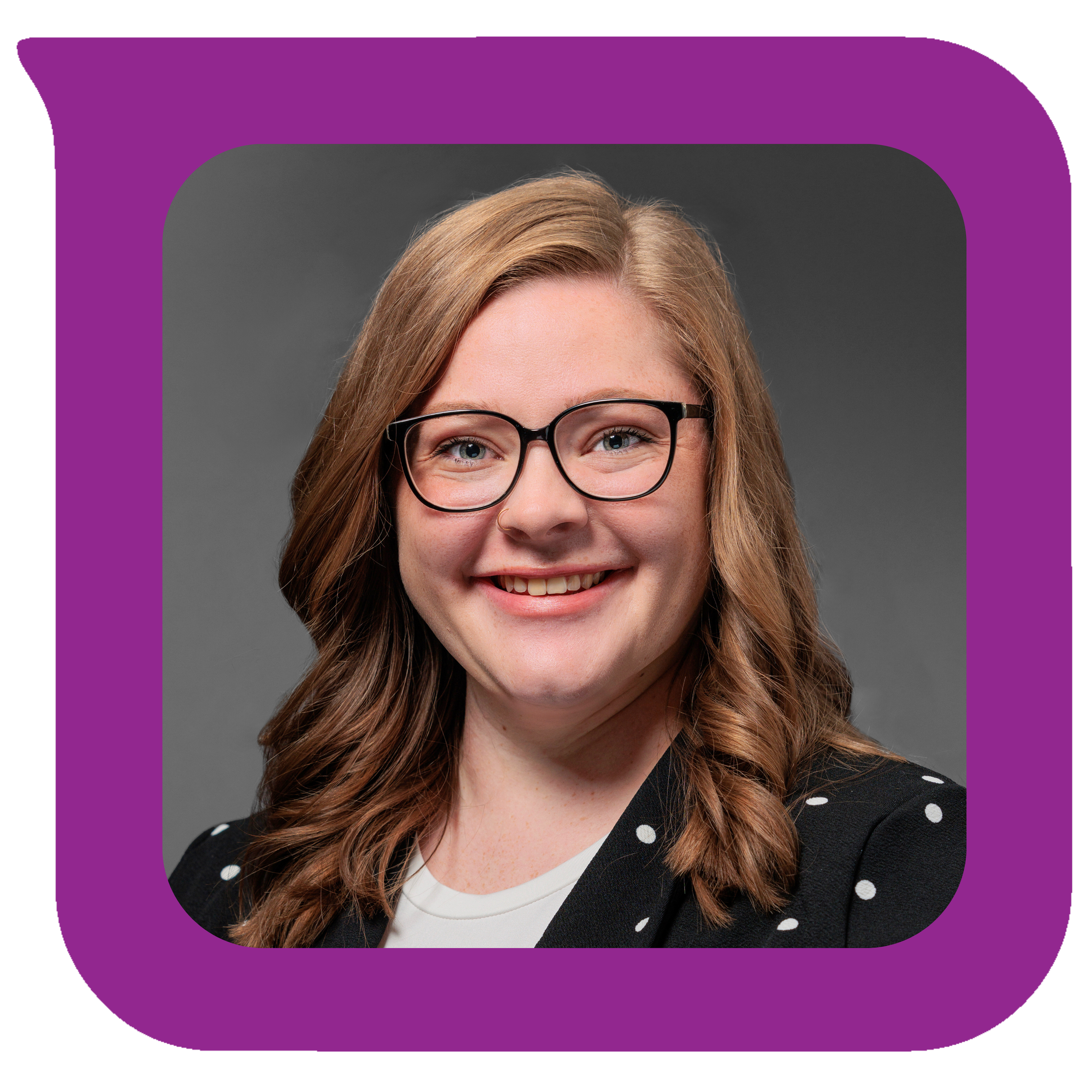 အညိုဖျော့ဖျော့၊ လှိုင်းတွန့်ဆံပင်၊ အနက်ရောင်ဘောင်တပ်မျက်မှန်၊ အဖြူရောင်အစက်အပြောက်ပါ အနက်ရောင်ဂျာကင်အင်္ကျီနှင့် အဖြူရောင်အပေါ်အင်္ကျီဝတ်ထားသော အမျိုးသမီးငယ်တစ်ဦးသည် မီးခိုးရောင်နောက်ခံတွင် ပြုံးနေသည်။