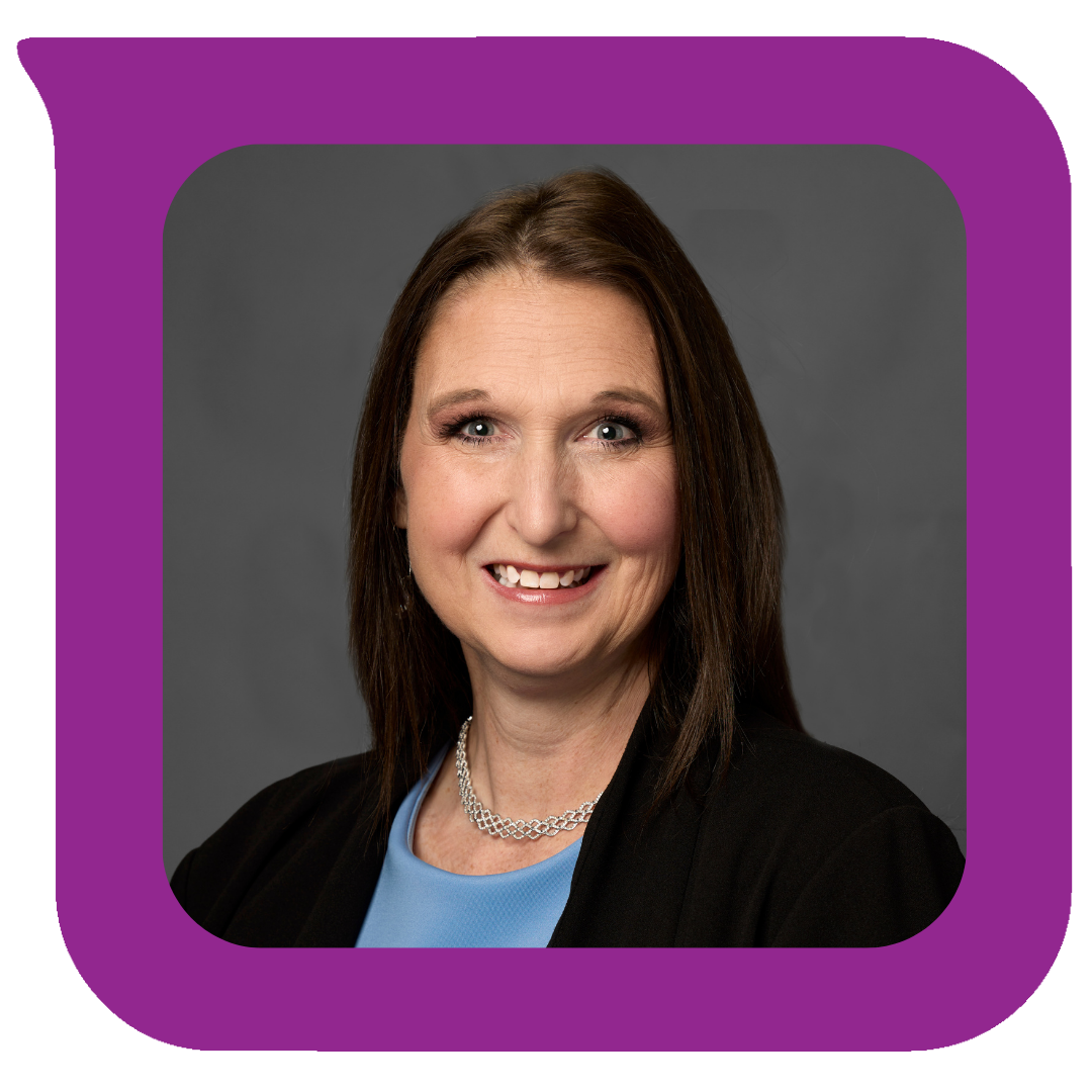 မီးခိုးရောင်နောက်ခံတွင် ပခုံးအထိရှည်သော အညိုရောင်ဆံပင်ရှိပြီး အနက်ရောင်ဘလေဇာအင်္ကျီ၊ အပြာဖျော့ရောင်အပေါ်အင်္ကျီနှင့် ငွေရောင်လည်ဆွဲဝတ်ဆင်ထားသည့် ပြုံးရွှင်နေသော အမျိုးသမီးတစ်ဦး၏ ပုံတူ။