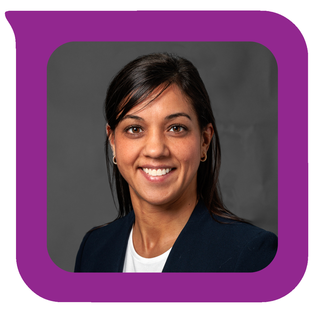 Professional headshot of a woman with dark hair, wearing a blazer and smiling, against a gray background.