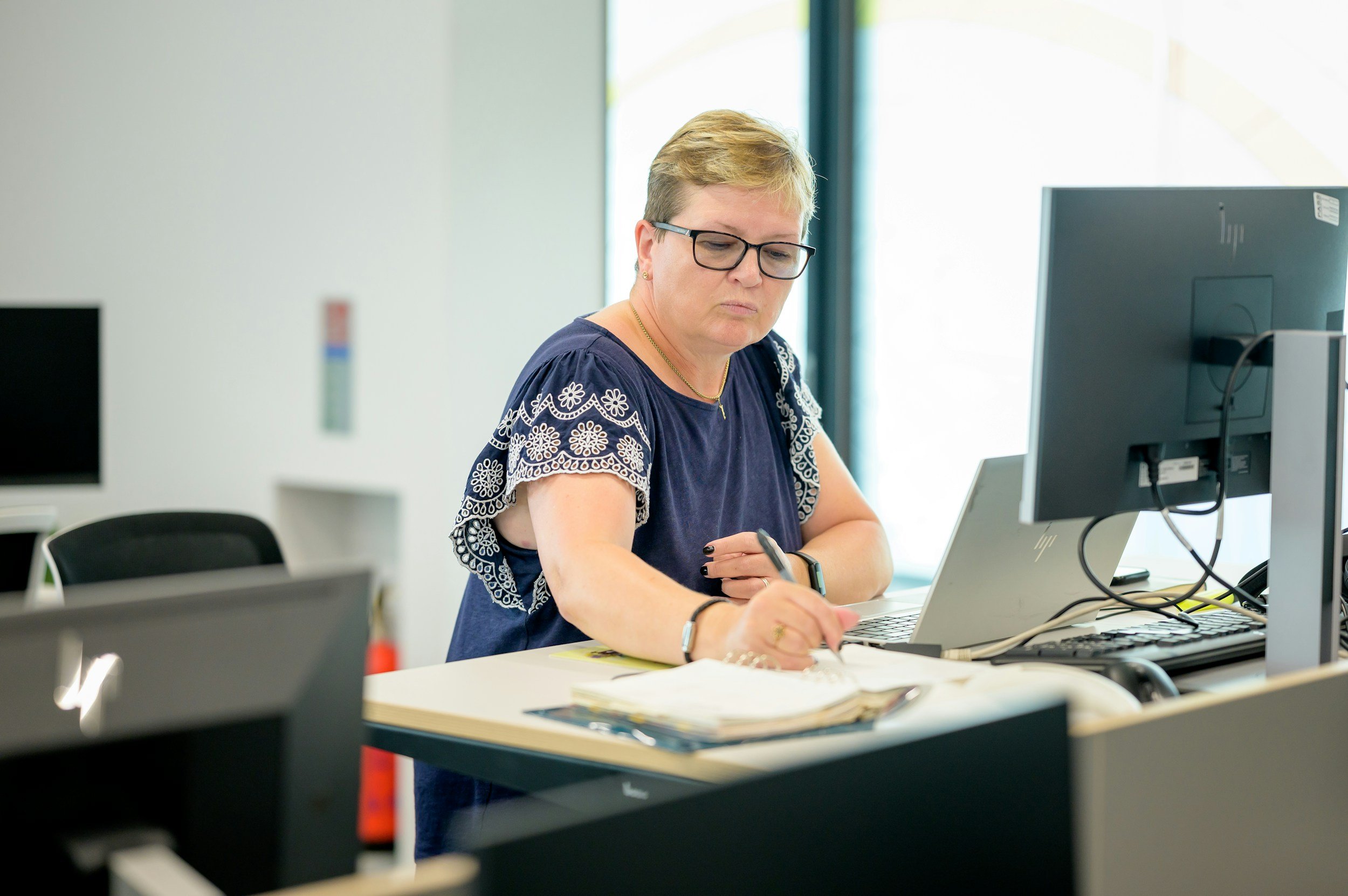 Senior woman taking notes while working on a laptop