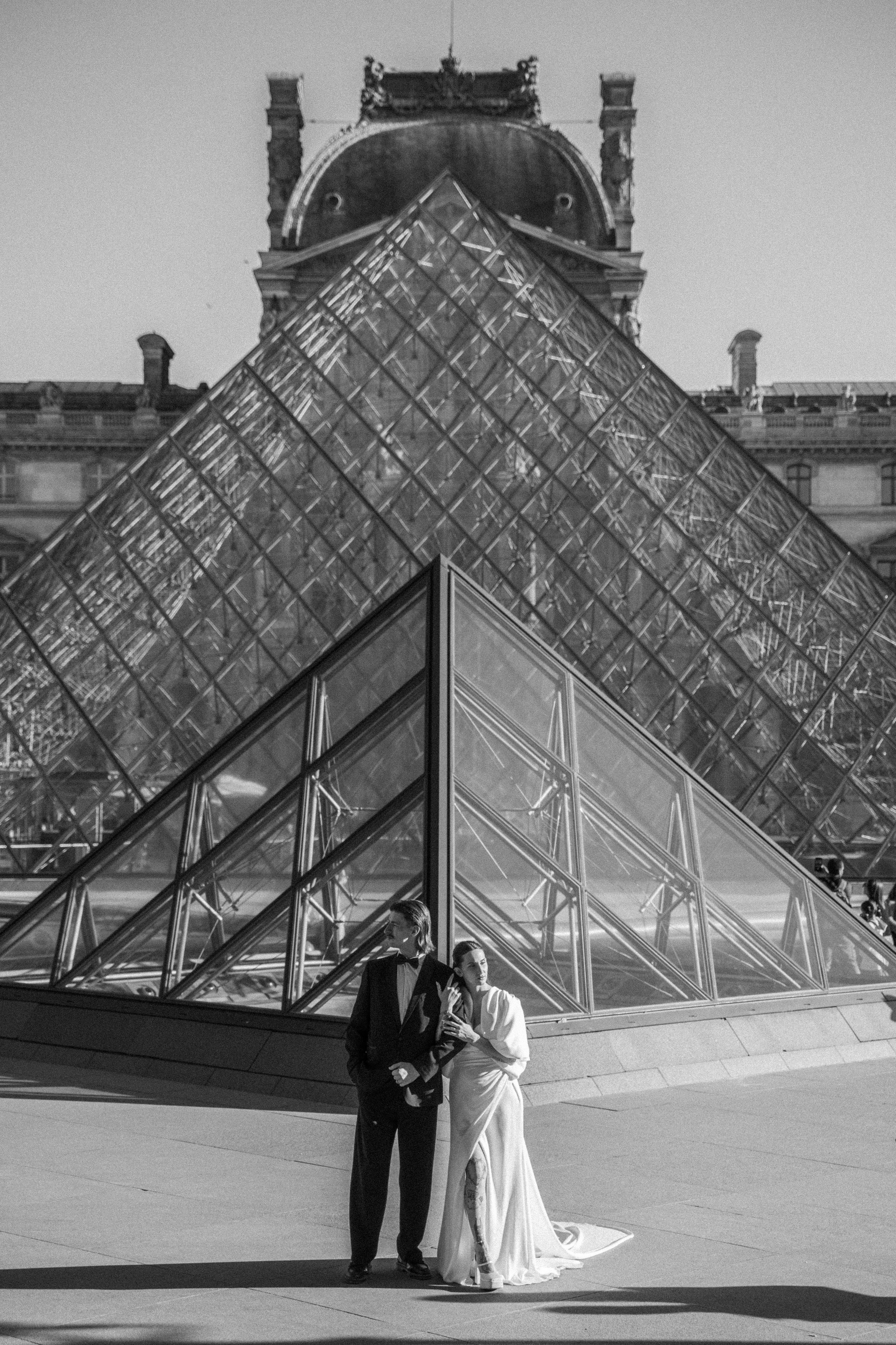man and woman stood in front of the louvre main museum building