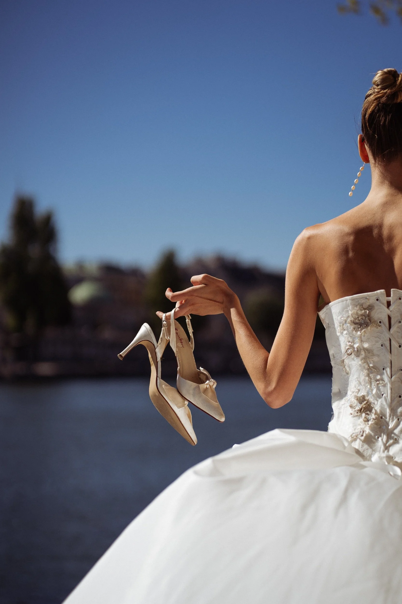 woman holding out high heels shoes overlooking the river in paris