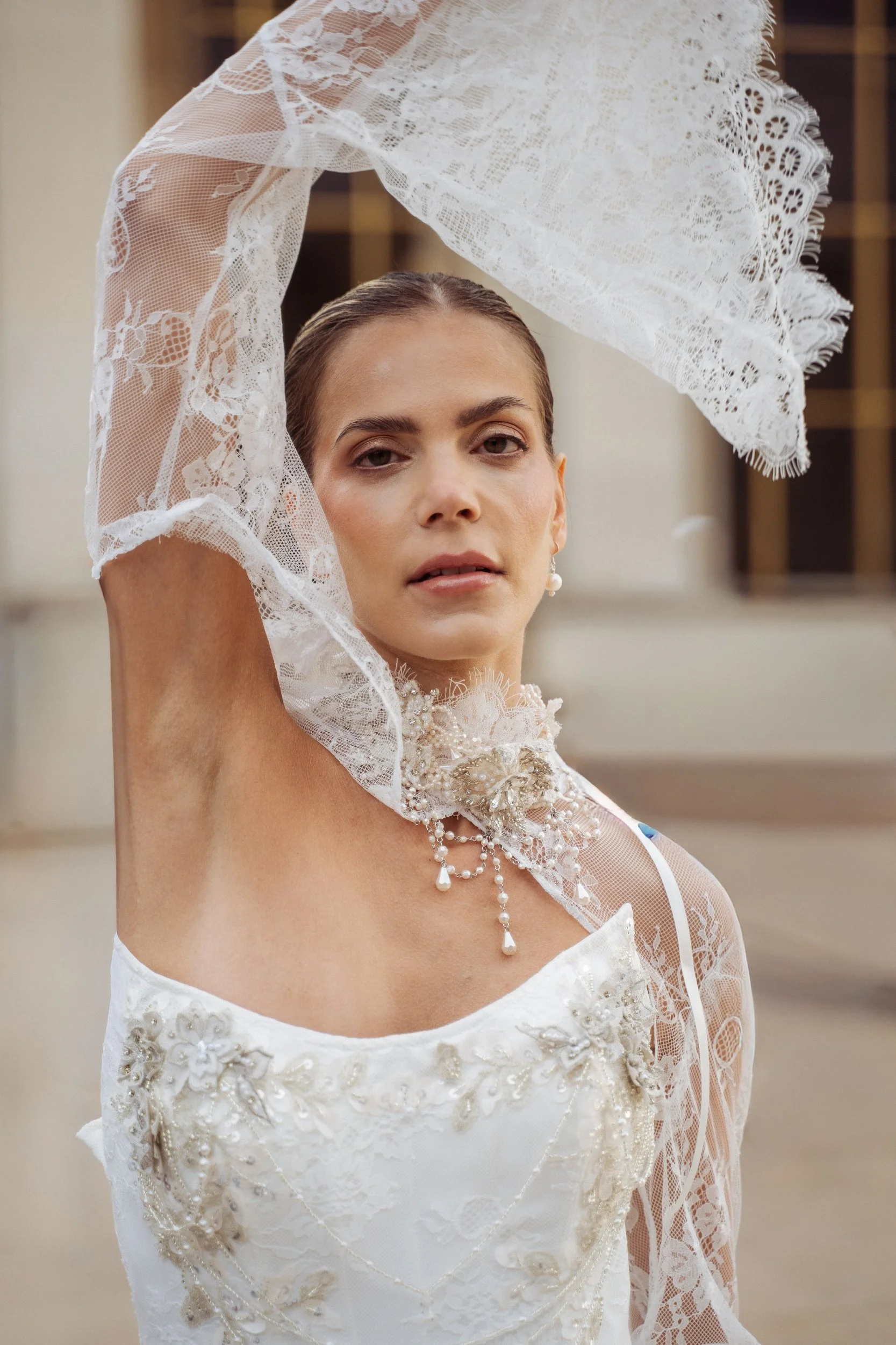 woman in wedding dress looking at camera whilst holding her arm up in the air