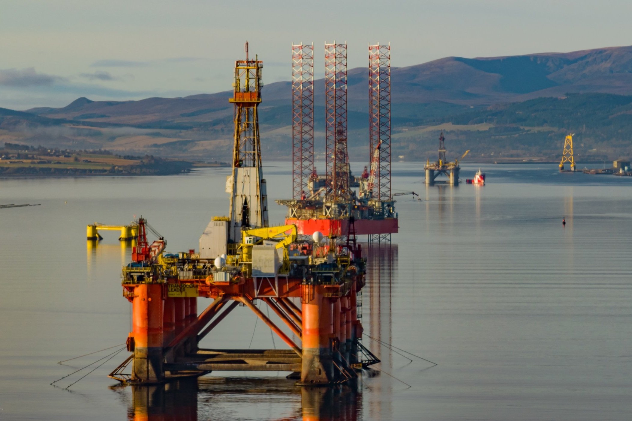 Offshore oil rigs in a body of water with distant hills
