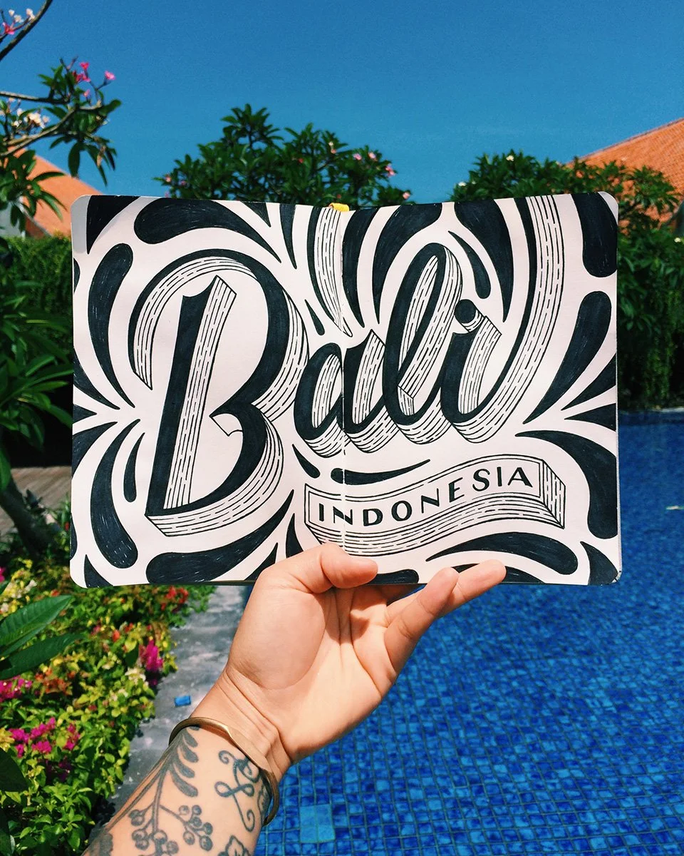 Detailed sketchbook spread reading "Bali, Indonesia" in dimensional hand-lettering surrounded by droplet-shaped flourishes.