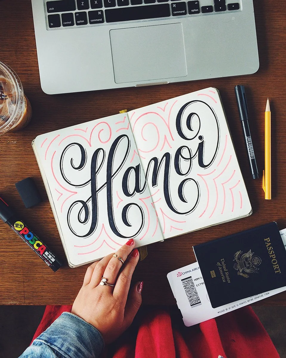 Sketchbook spread reading "Hanoi" surrounded by flourishes.