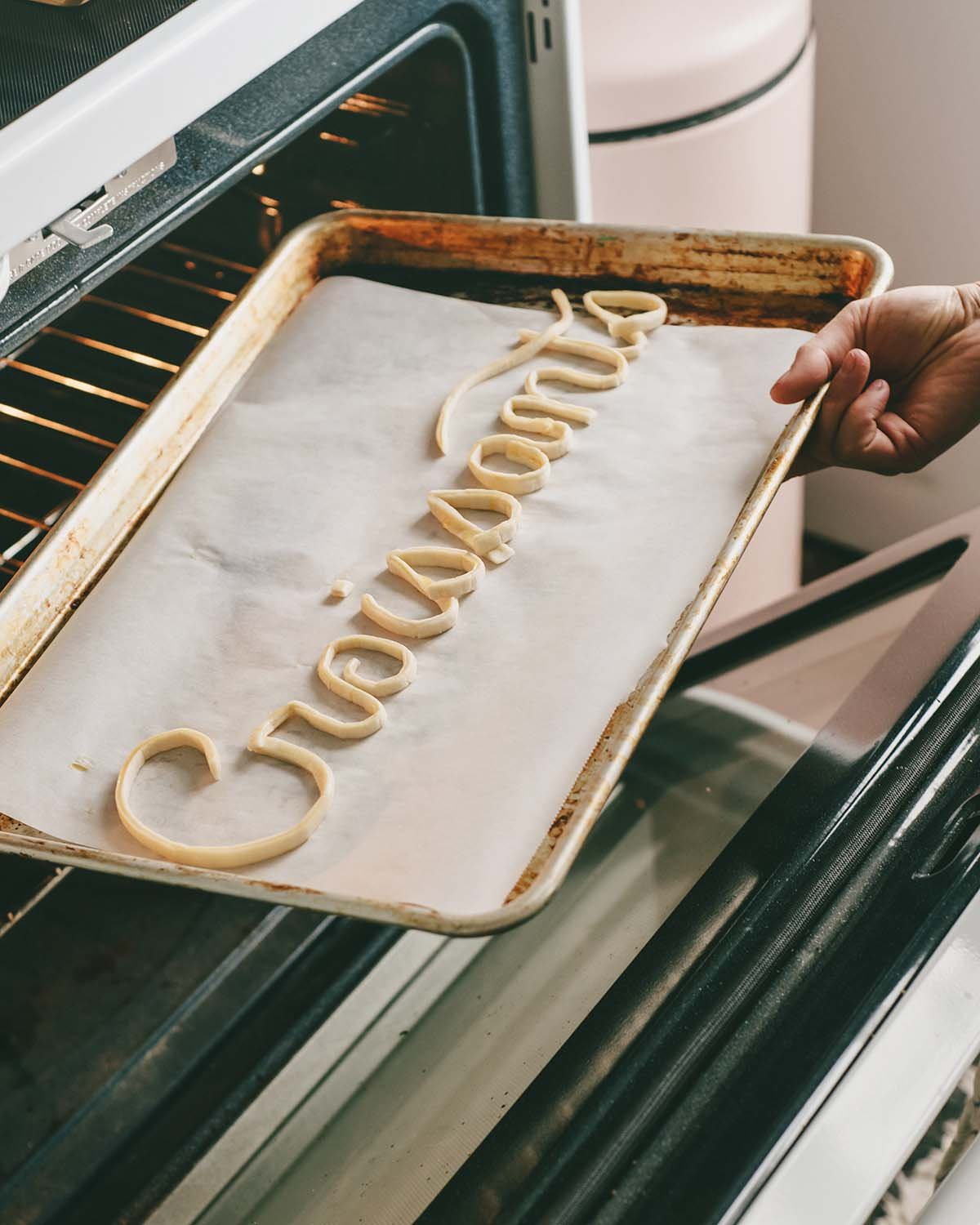 Lauren places puff-pastry lettering into the oven.