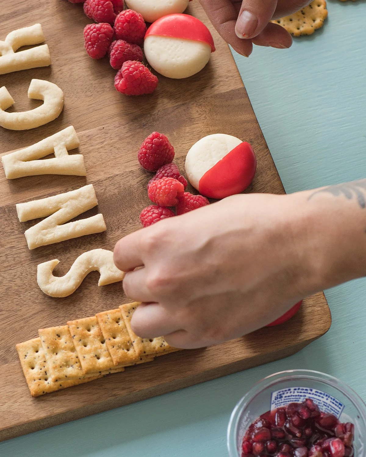 Lauren placing raspberries onto the Babybel "You Deserve a Snack" charcuterie board.