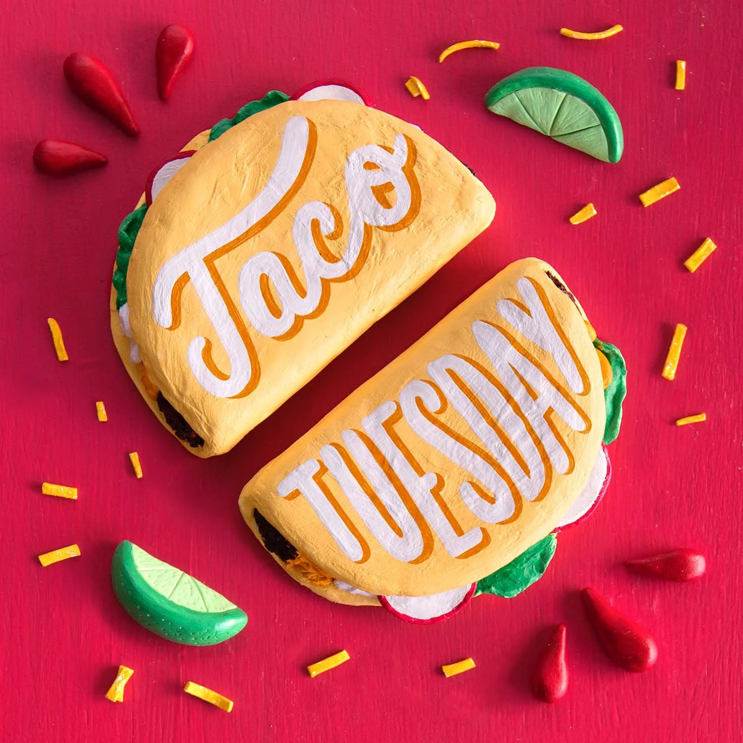 Two stuffed tacos made from clay reading 'Taco Tuesday' are surrounded by clay cheese, limes, and flourishes on a red background.