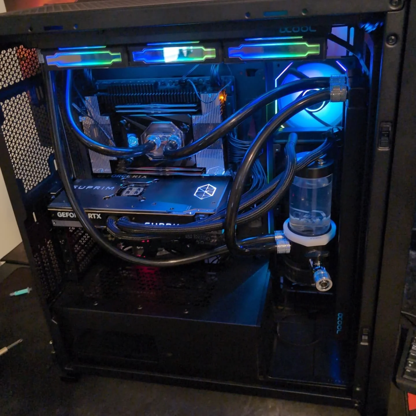 A gaming computer with liquid cooling, LED-lit components, a graphics card, a CPU water block, and a case with transparent glass panels.