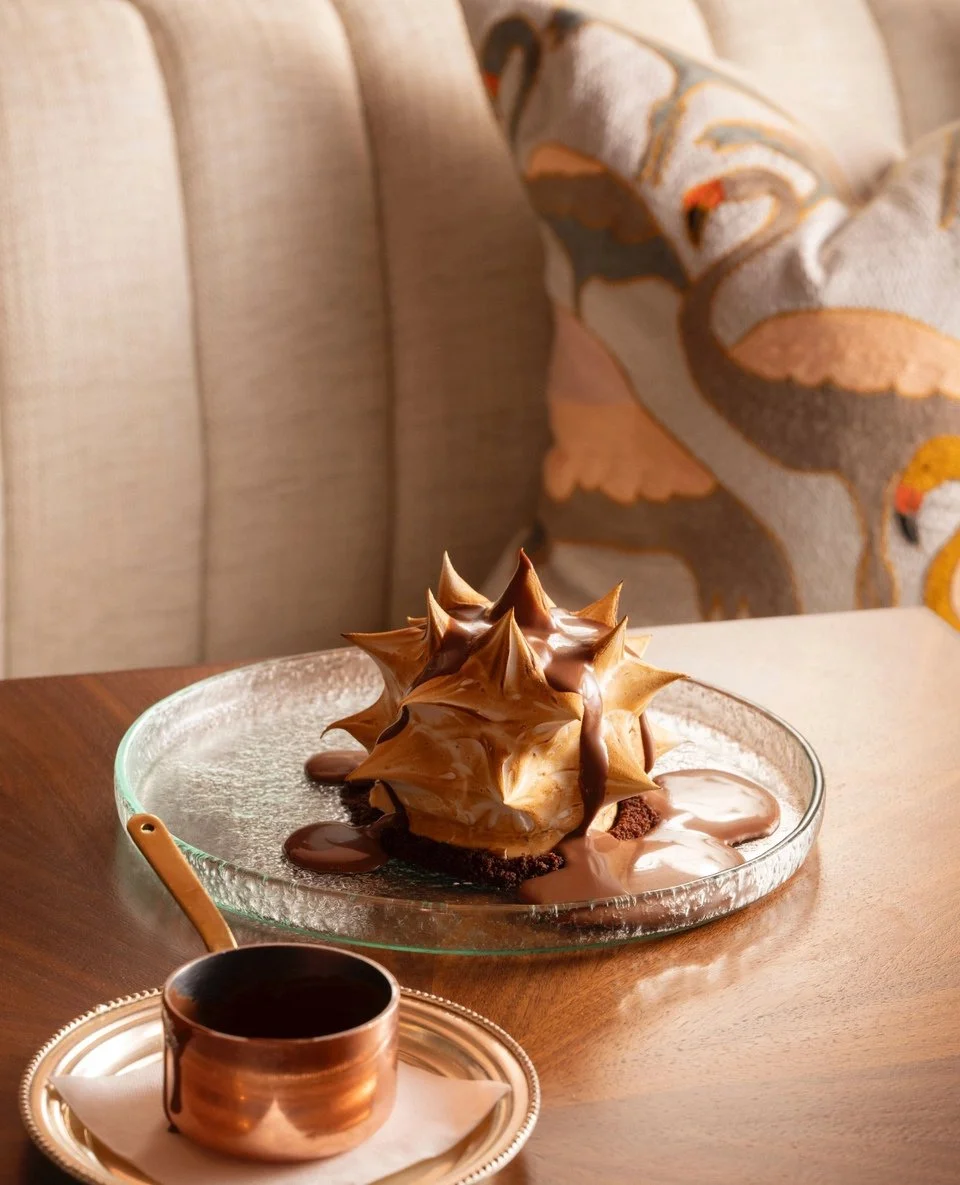 Some dishes feel timeless the moment they arrive at the table. Our Flamingo Room Baked Alaska is one of them. Layers of dark chocolate ganache, choco-sponge and vanilla semifreddo sit beneath peaks of golden meringue, finished with warm caramel and c