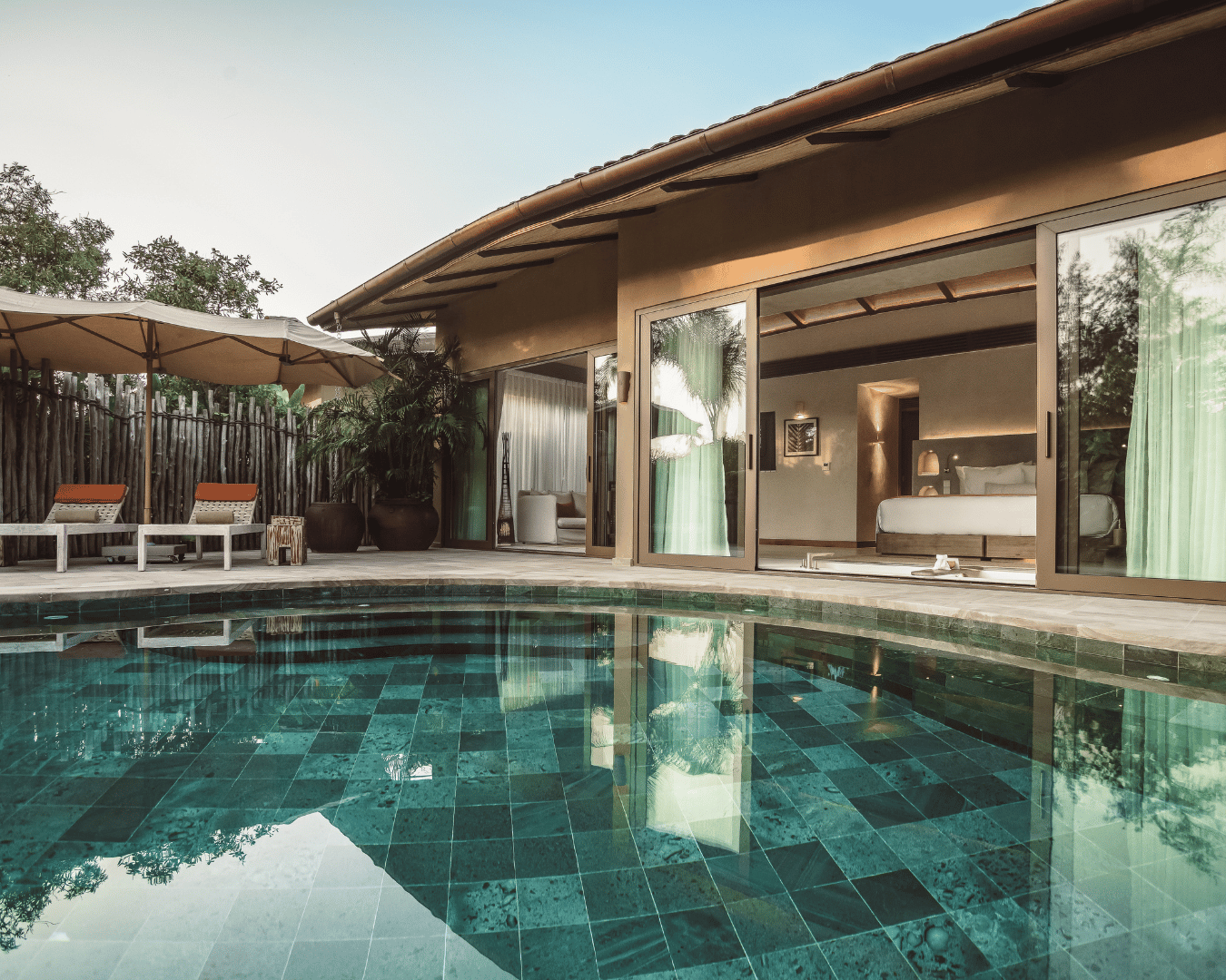Luxury house with a swimming pool outdoor patio area and a bedroom visible through large glass sliding doors. | Awakened Soul - Jessika Harrison 