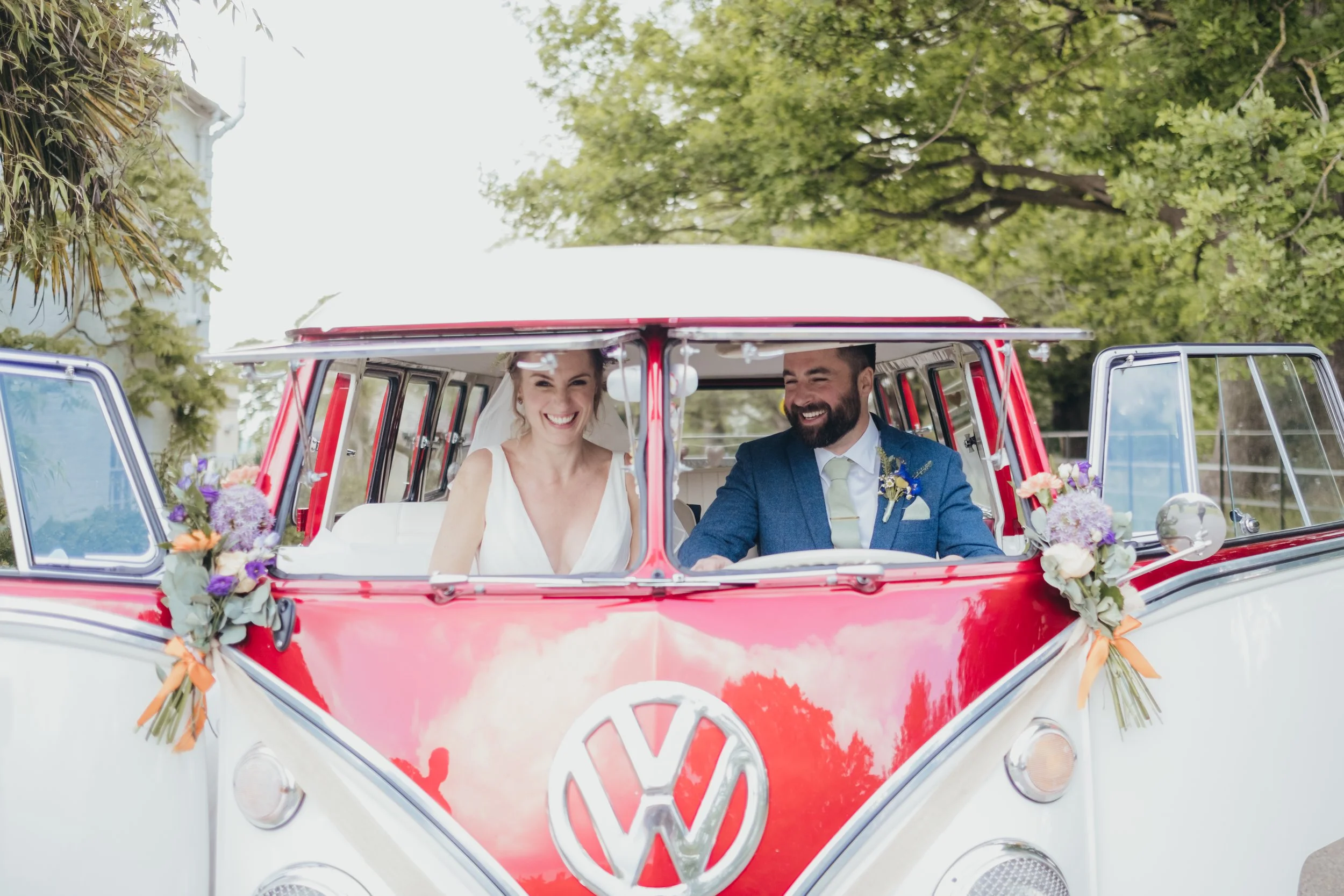 Bride and Groom having portraits in a red quirky wedding VW split screen camper.