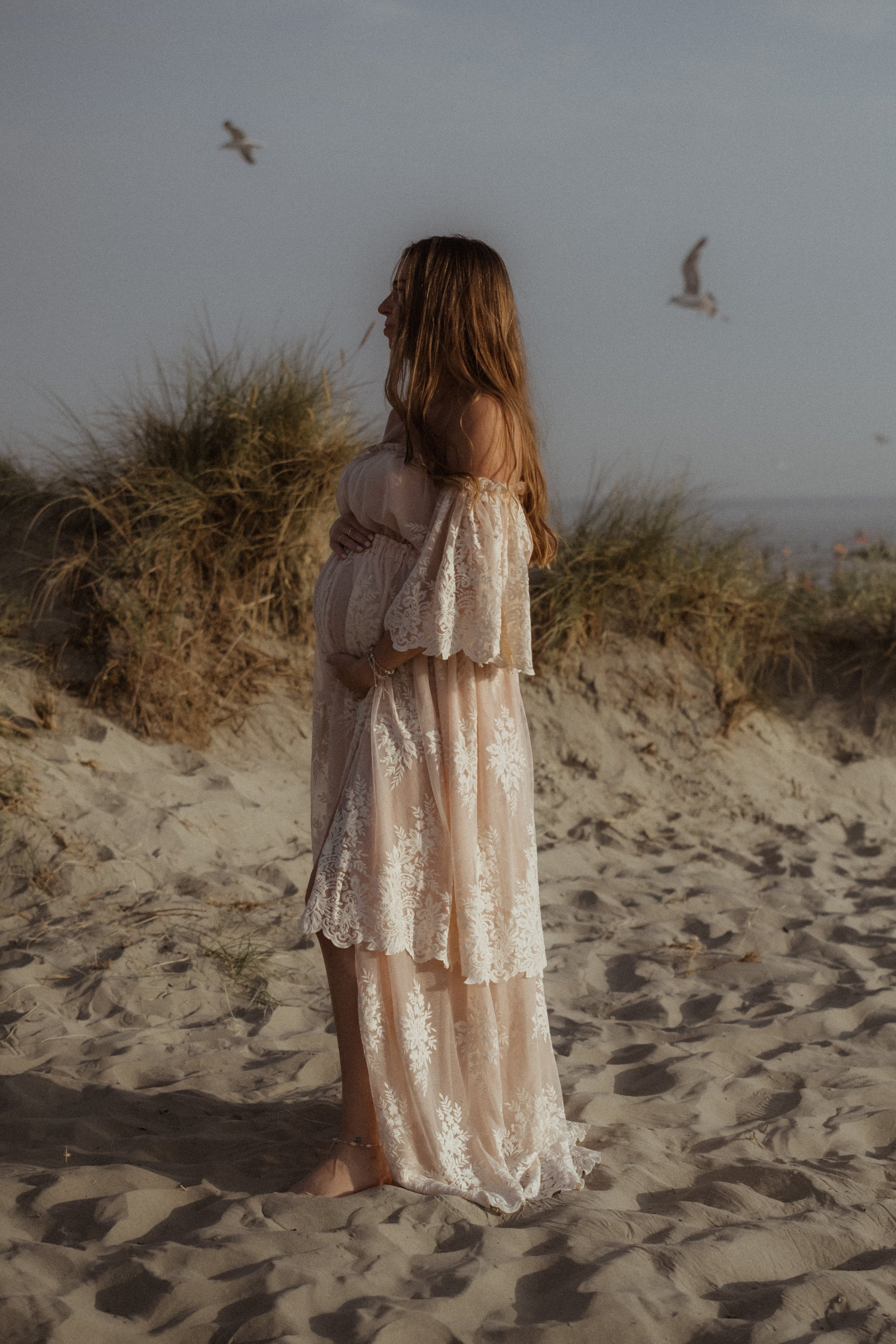 Mother-to-be in a flowing boho dress cradling her baby bump, surrounded by natural light and soft earthy tones, capturing the serene essence of pregnancy