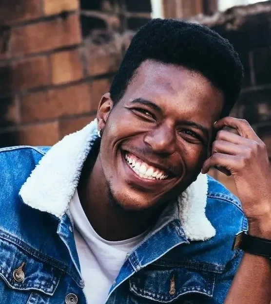 A colored man smiling with a blue jacket on