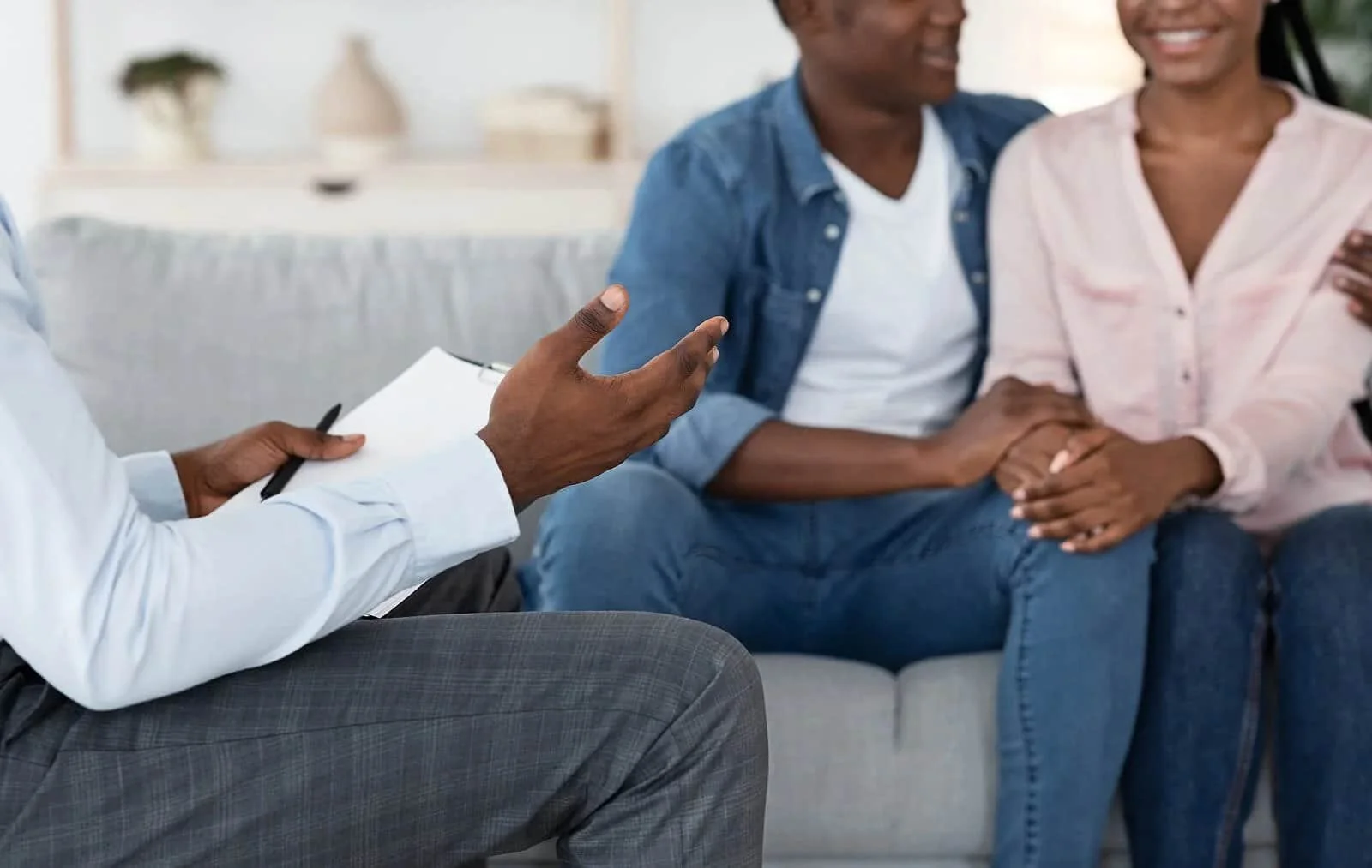 A couple smiles while sitting across from a person with a clipboard and gesturing with their hands. Learn more about therapy for intimacy issues in Walnut Creek, CA and how a couples therapist in Walnut Creek, CA can help