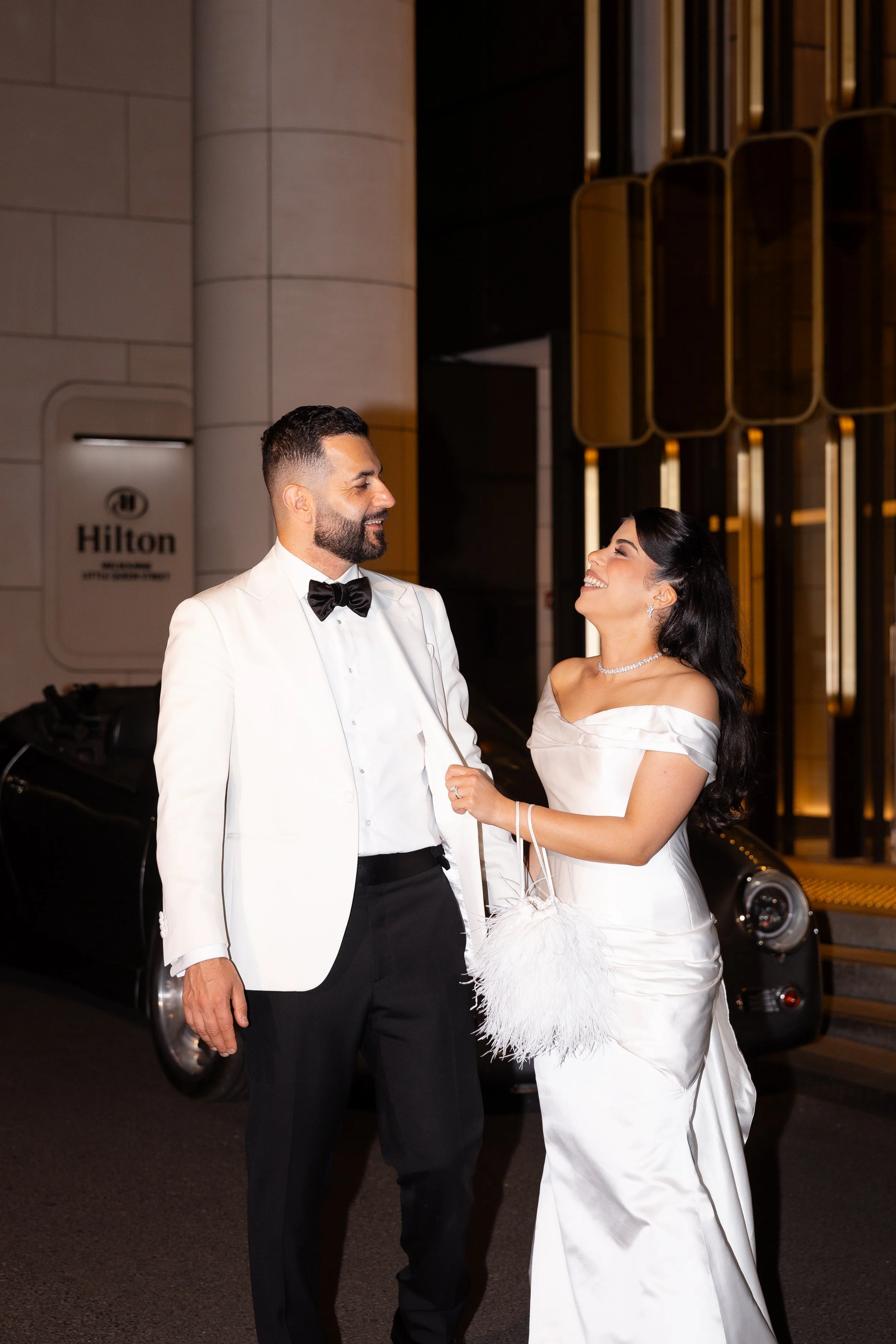 Jihan and Rob walking arm in arm outside the hotel entrance at night