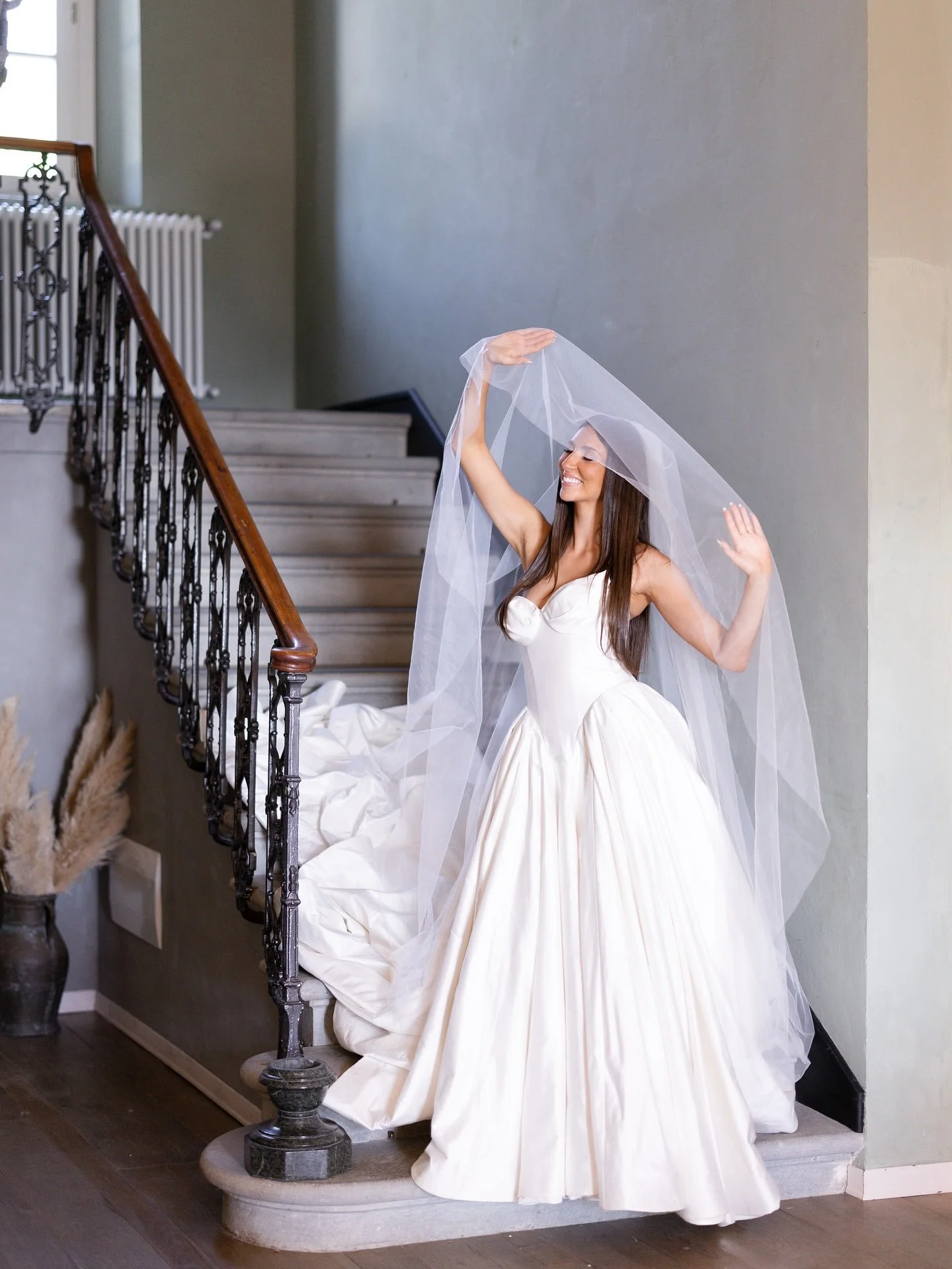 Marilena in her wedding gown lifting her veil on a staircase at Villa Belvedere, Tuscany