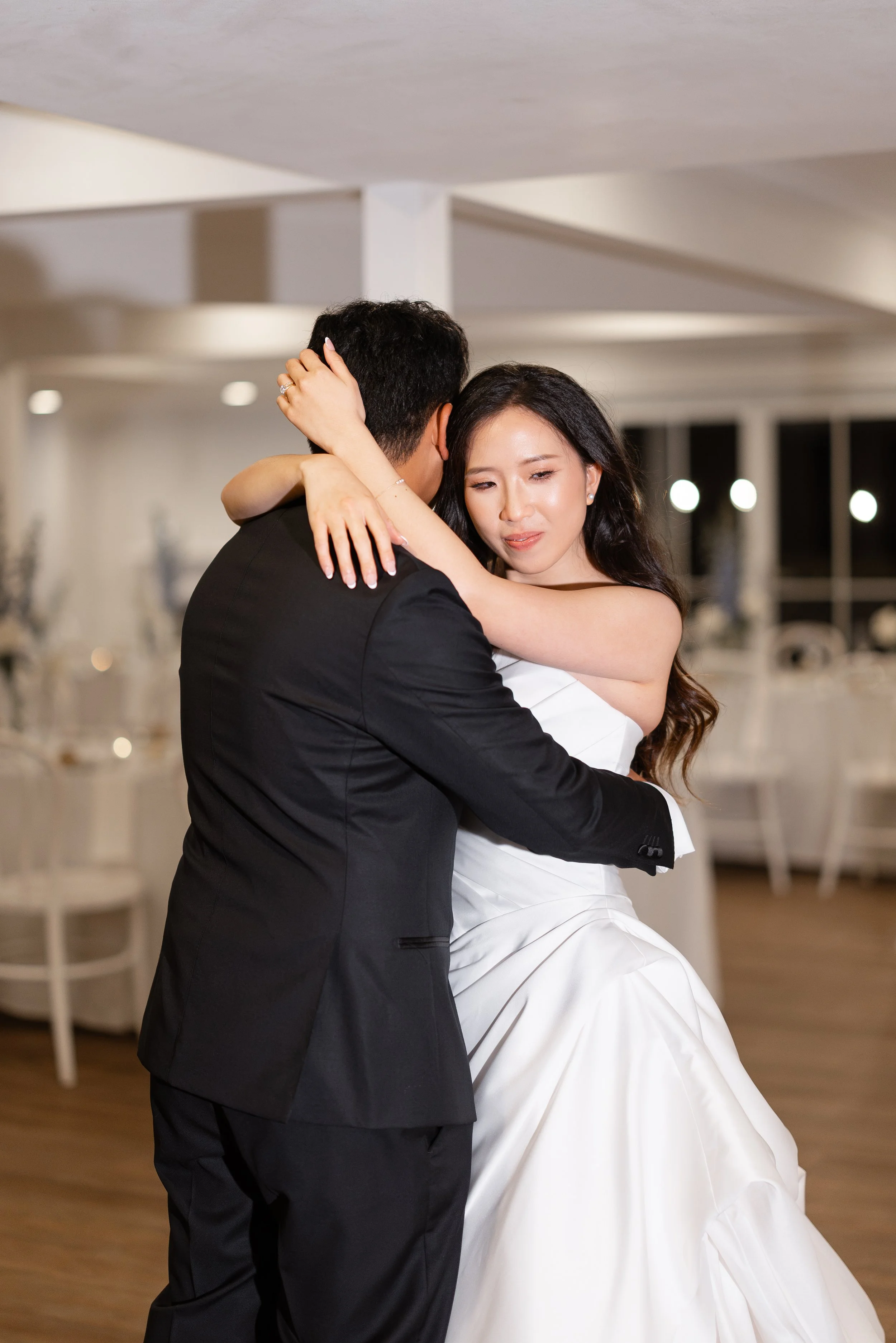 Alicia and Ezra slow dancing and embracing in a bright room with a wooden floor