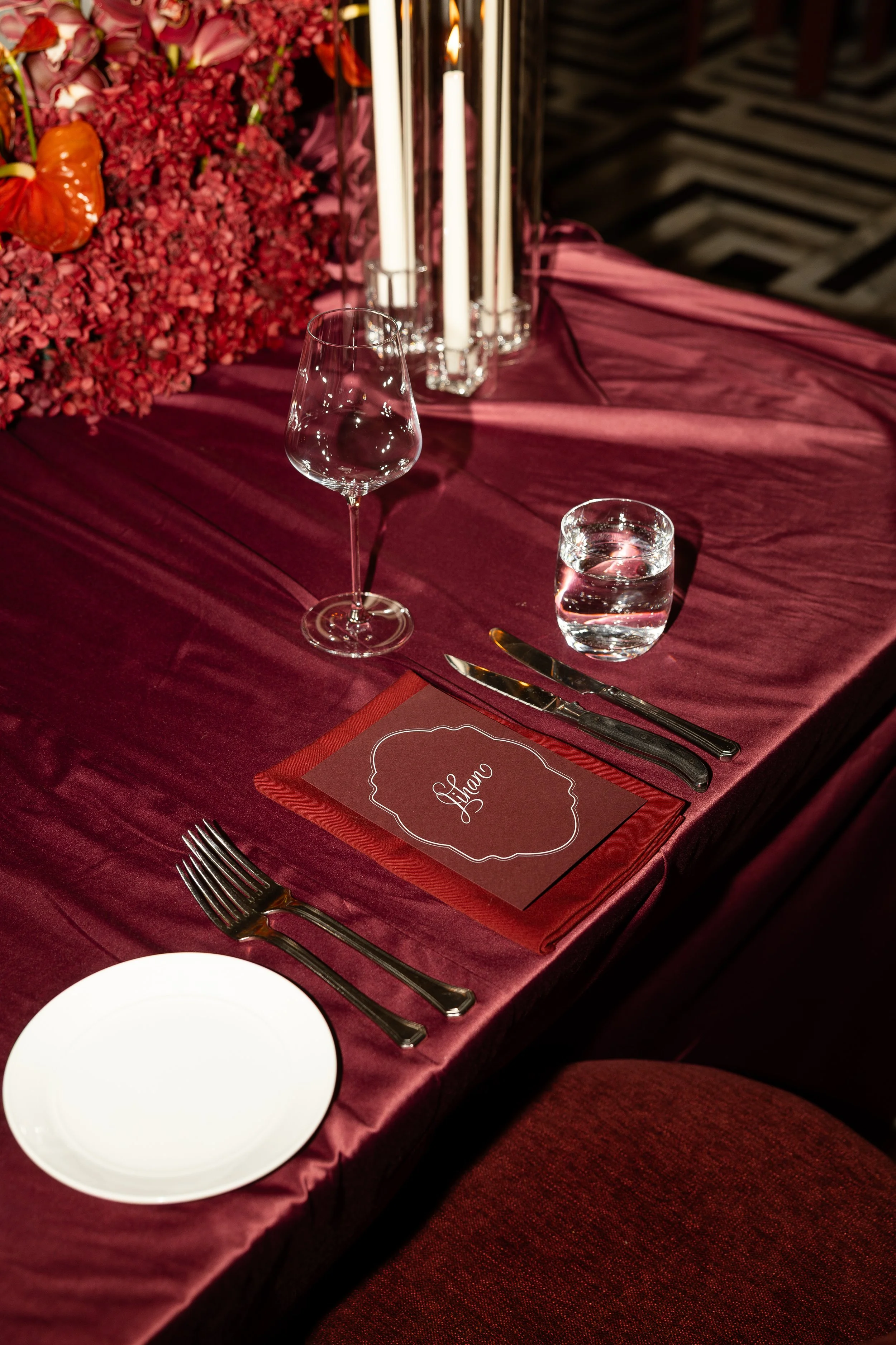 Jihan and Rob’s burgundy reception table setting with candles and florals at Luci Melbourne