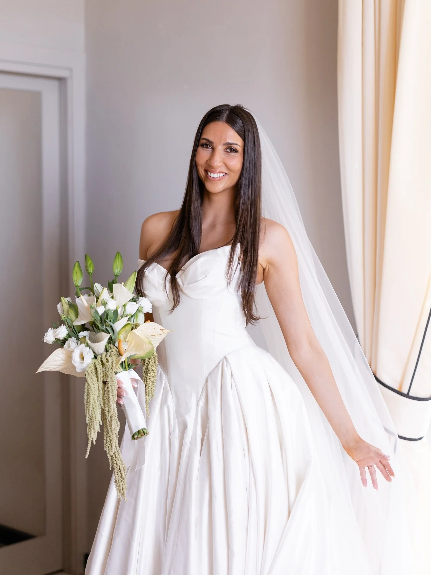 Bride Marilena holding her bouquet in her gown and veil on the morning of her Tuscany wedding