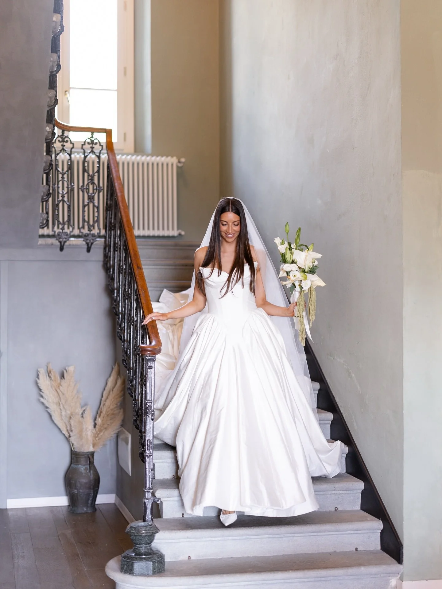 Bride Marilena in her gown and veil on the villa staircase