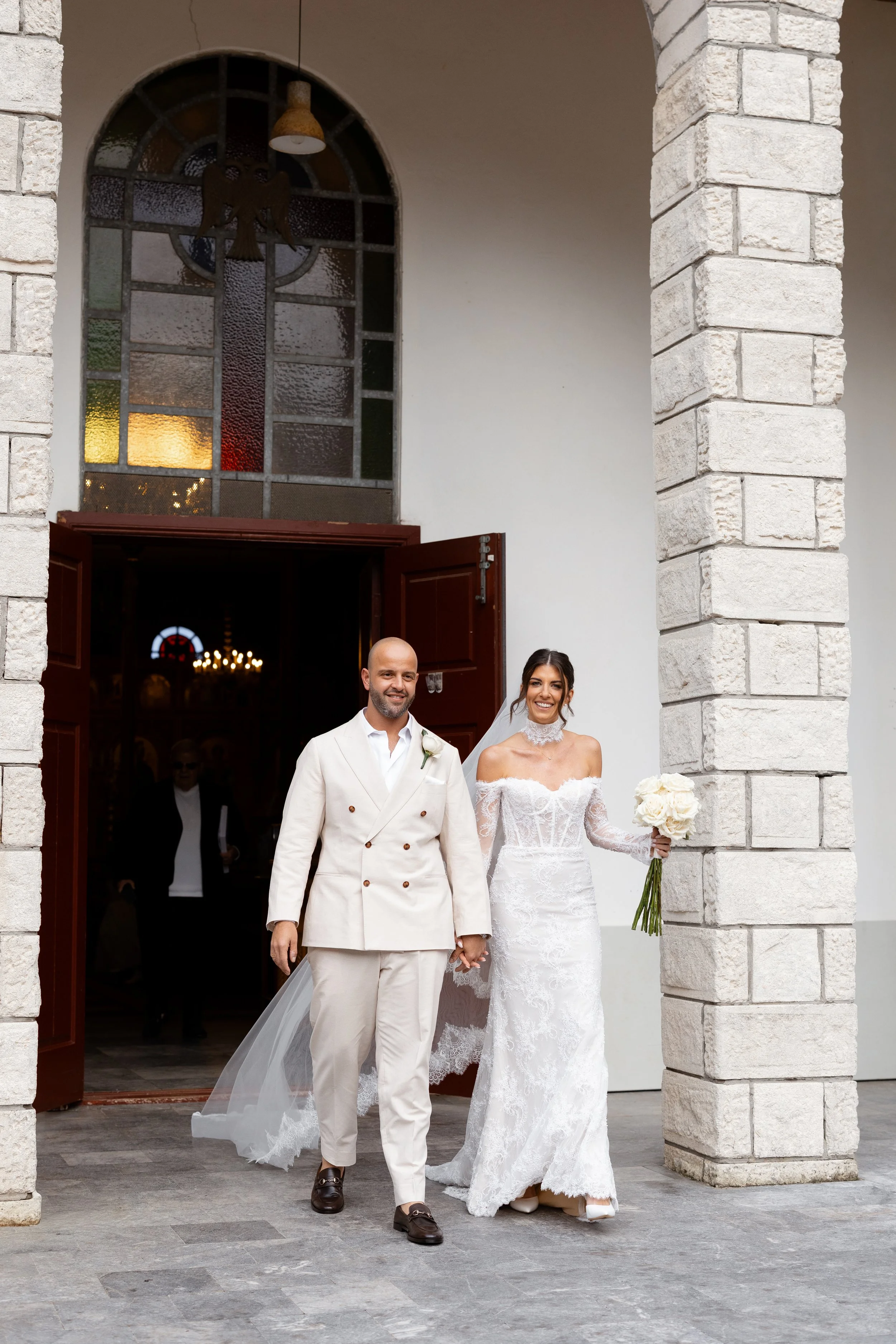 Steph and Alex walk out through the church doors after their ceremony