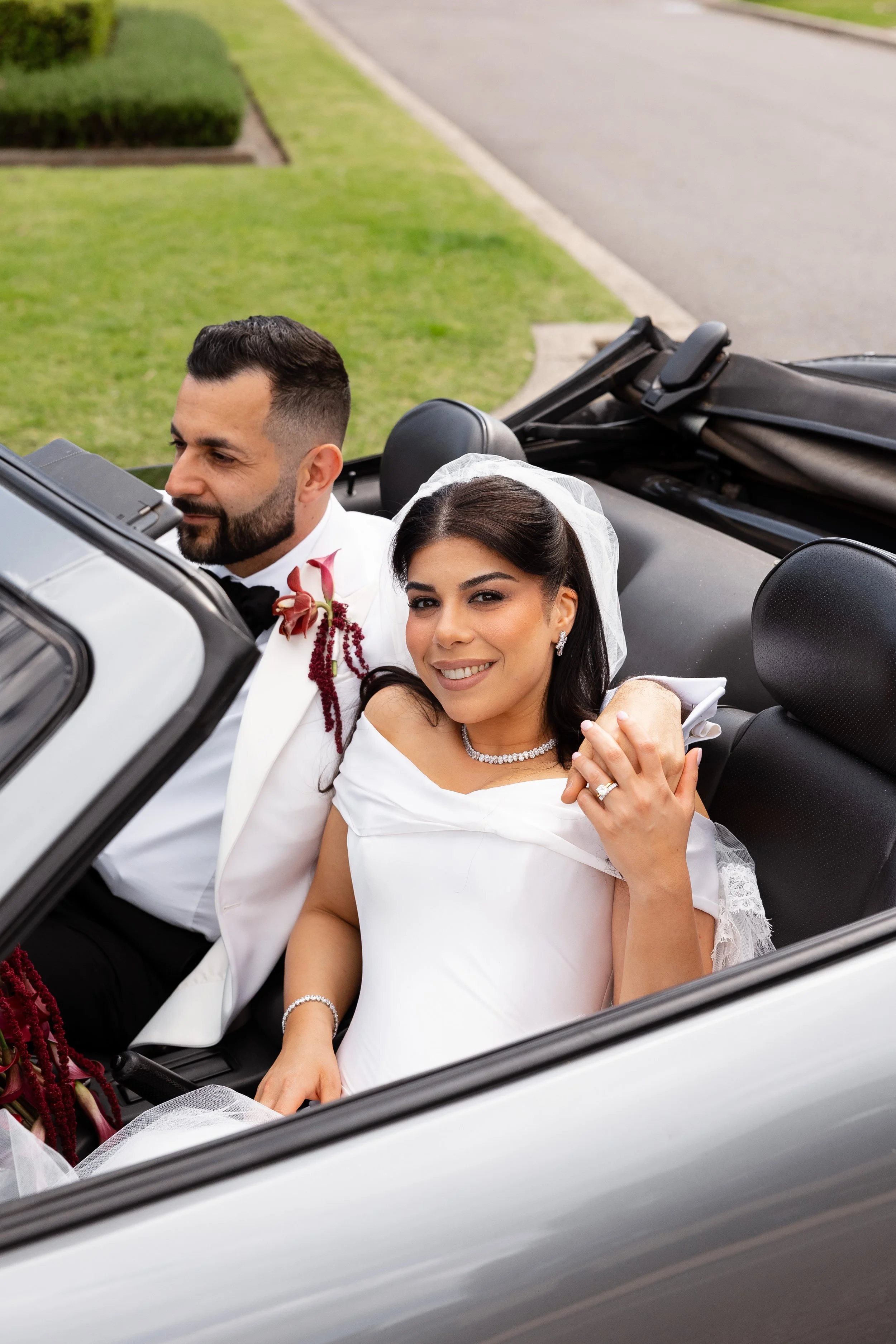 Jihan and Rob laughing together in an open classic convertible