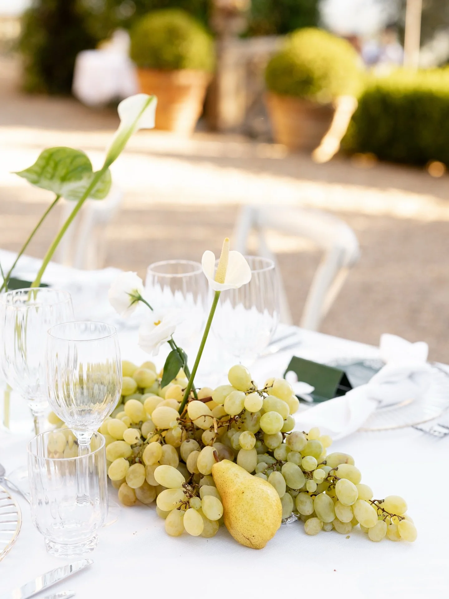 Wedding table detail with green grapes, a pear, white flowers and glassware at Villa Belvedere, Tuscany