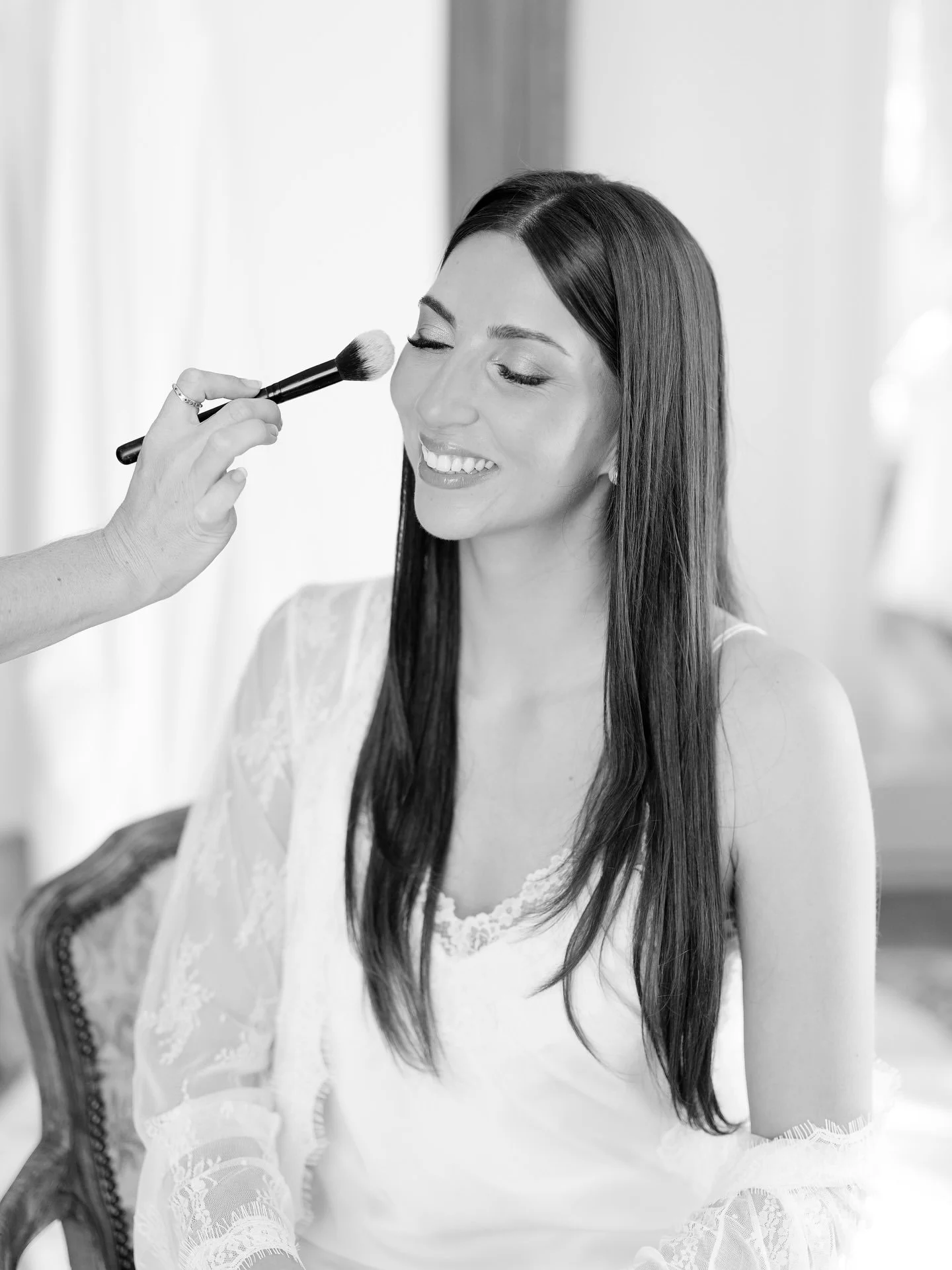 Black and white photo of Marilena having her wedding makeup applied by Holly Fraser