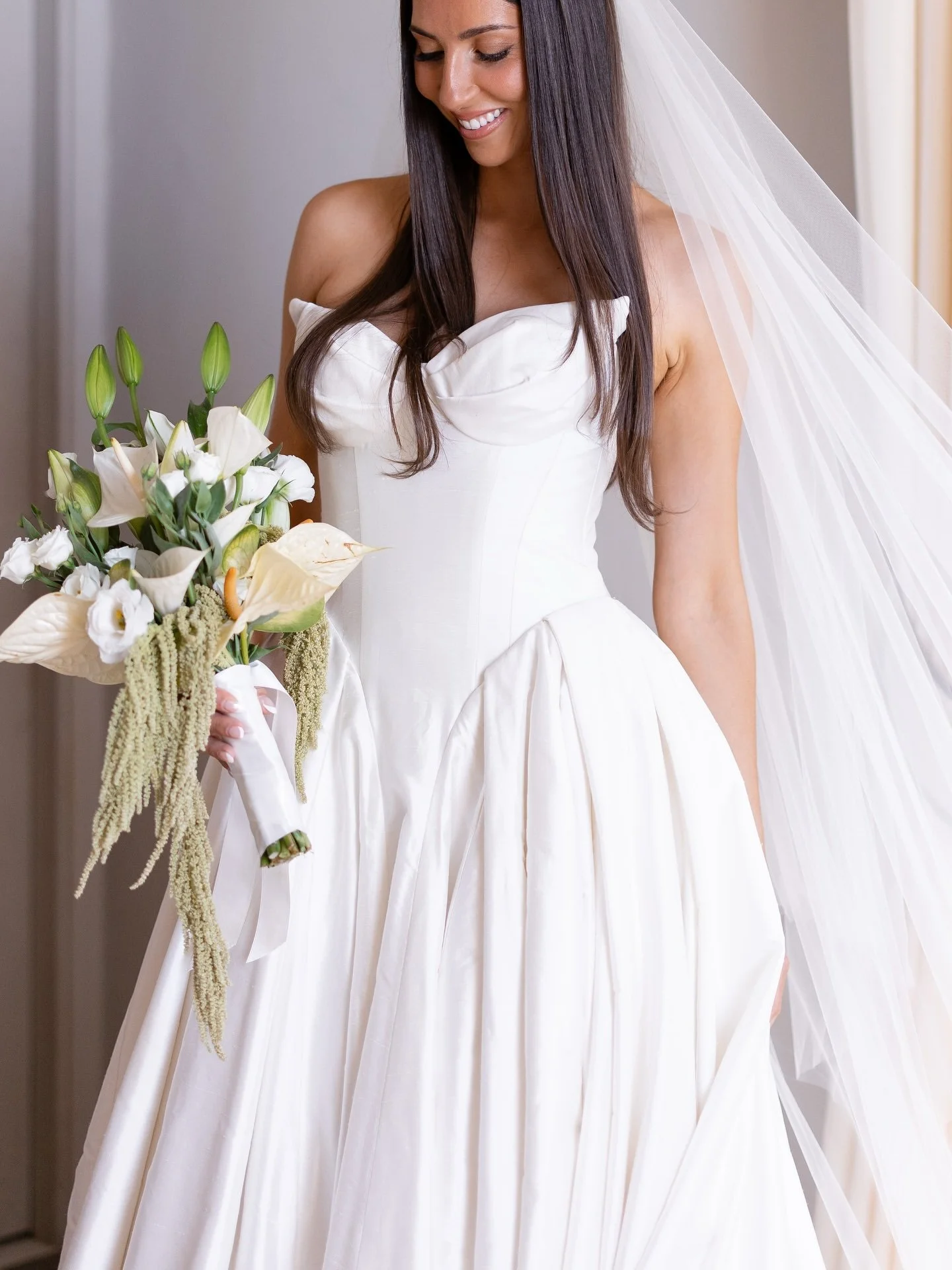 Marilena in her strapless wedding gown and veil holding a trailing bouquet