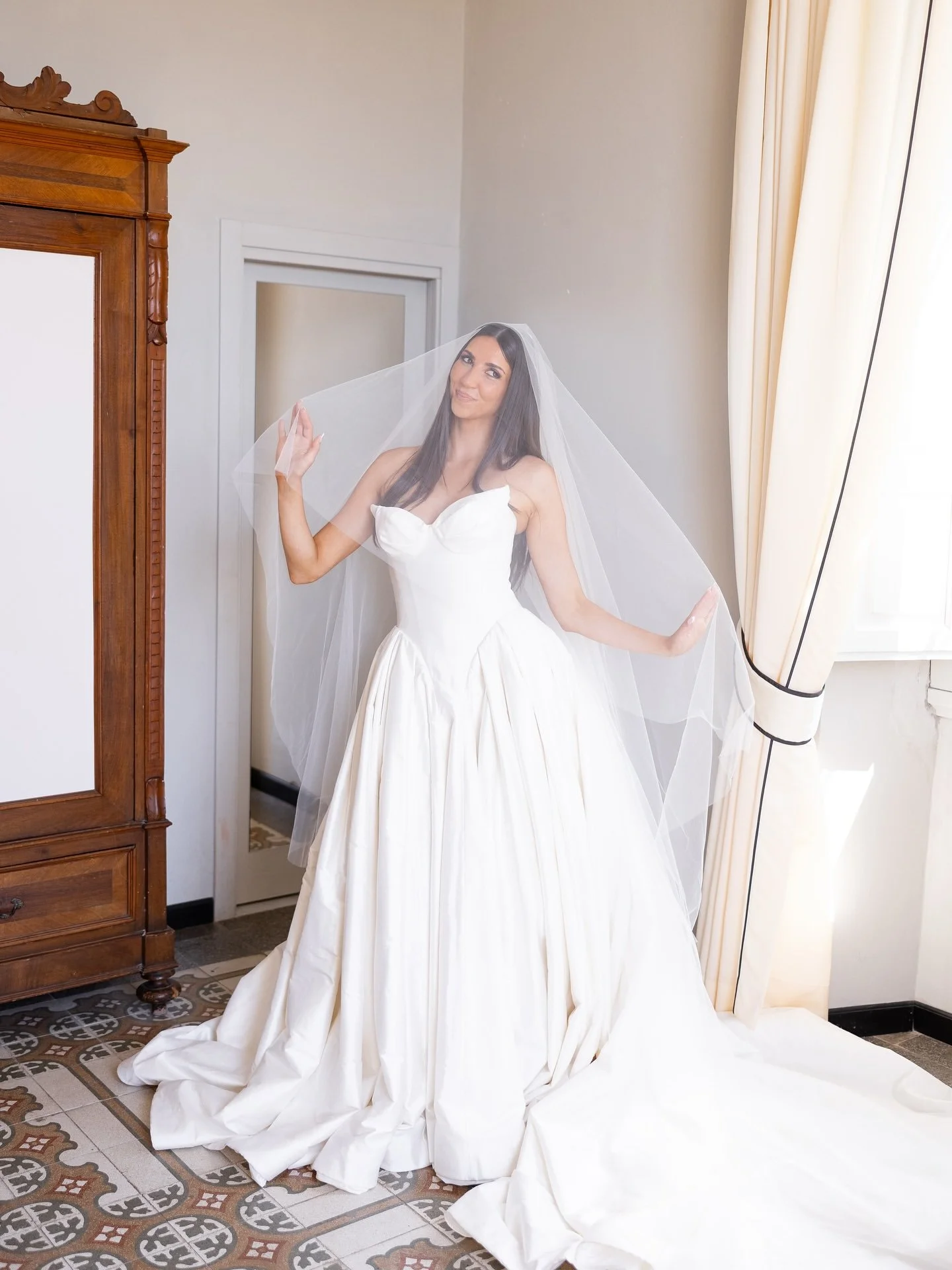 Bride in her wedding gown standing in a sunlit room of the villa