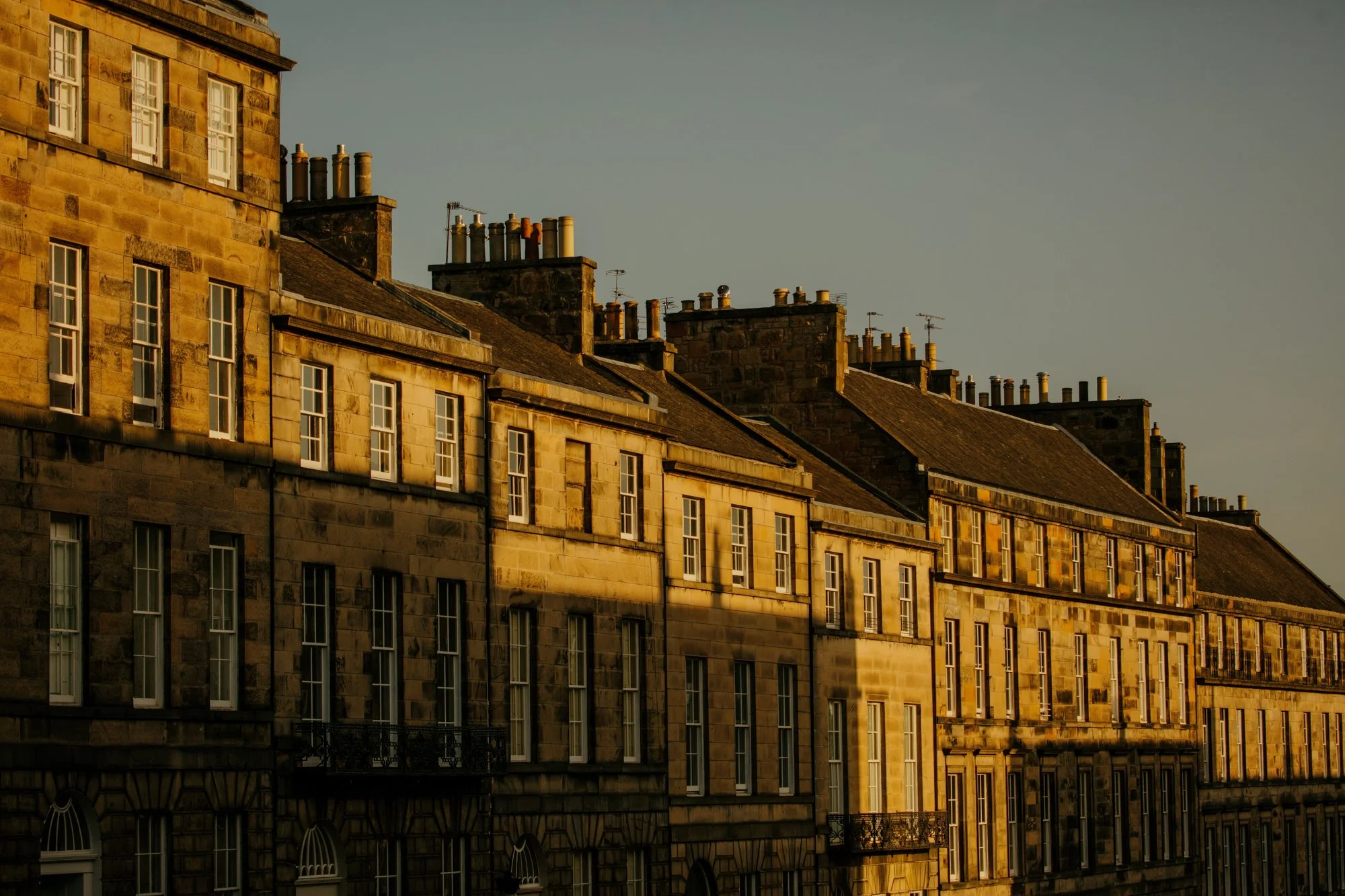 Golden house sunlight on India Street in Edinburgh's New Town, with multiple chimneys and tall windows.
