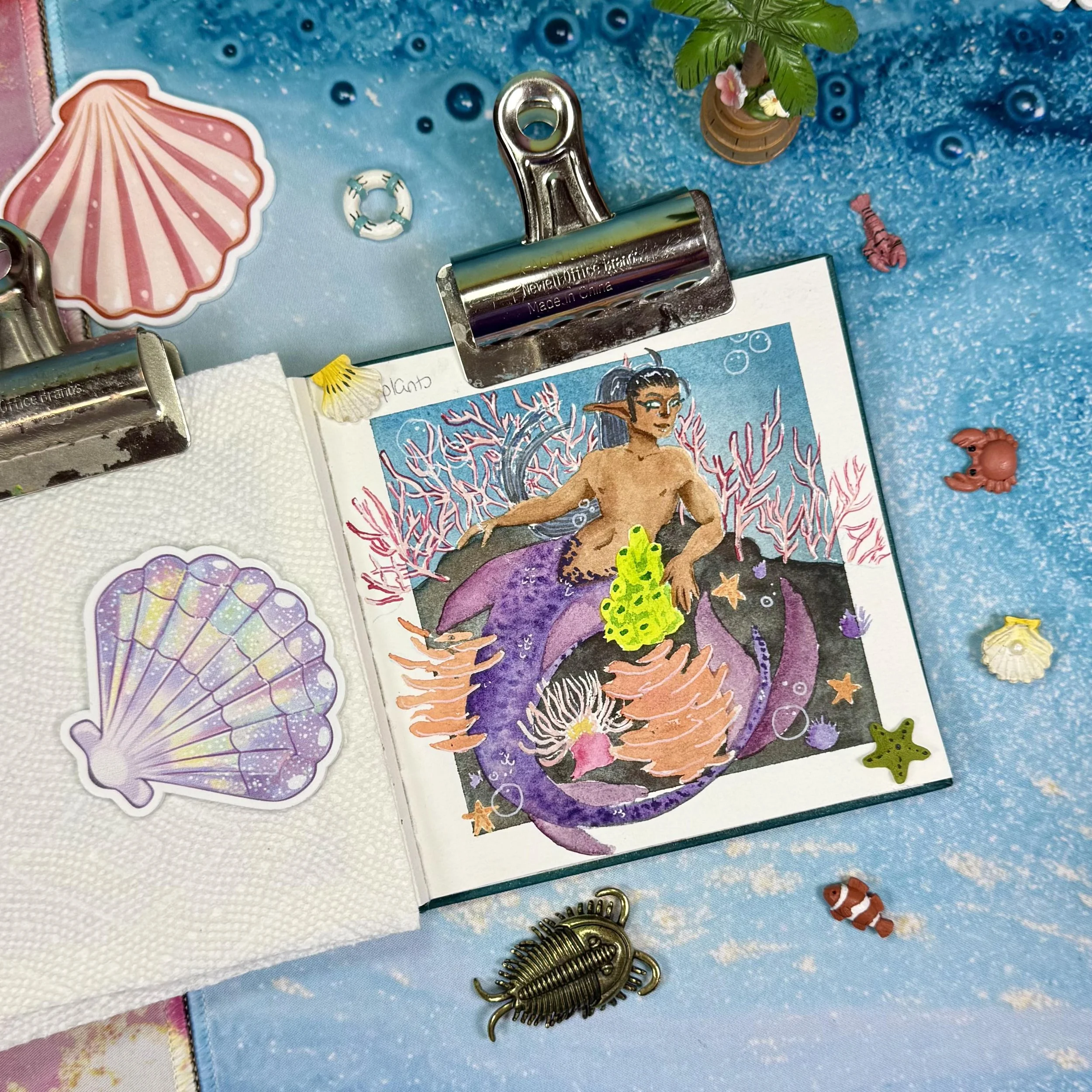 A mermaid sitting, surrounded by corals, anemones, starfish, and urchins