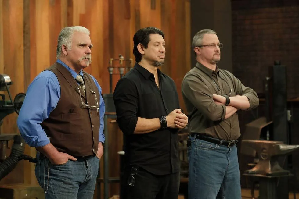 The Forged In Fire judges stand in front of contestants.