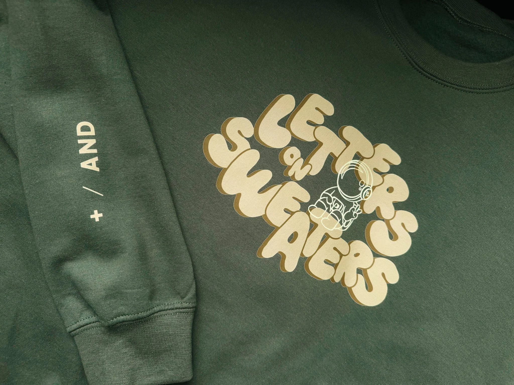 Close up of bubble lettering and moon man illustration on crewneck sweater