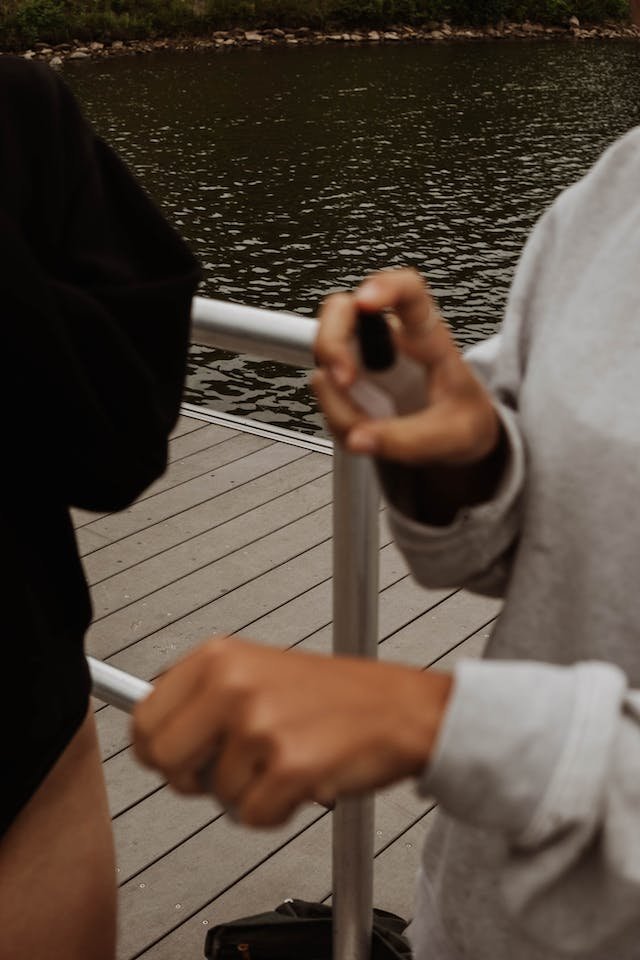 wo girls by the water, one spraying fragrance on her hand, representing the Road to Recognition in brand identity development.
