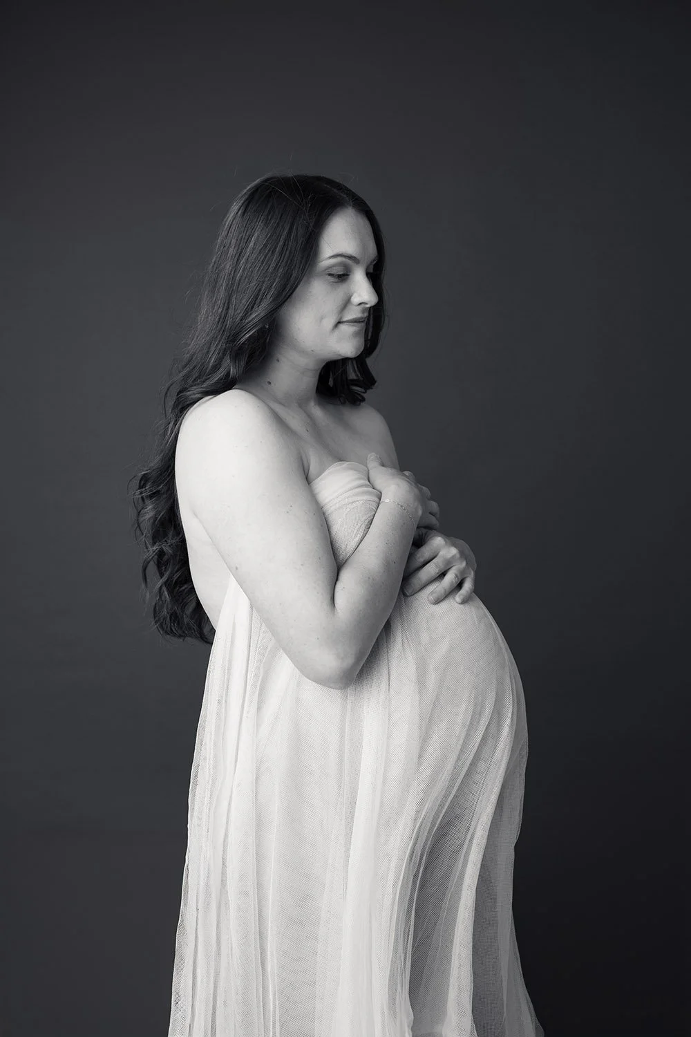 Elegant maternity portrait of an expecting mother in soft studio lighting, photographed by a Utah County maternity photographer.