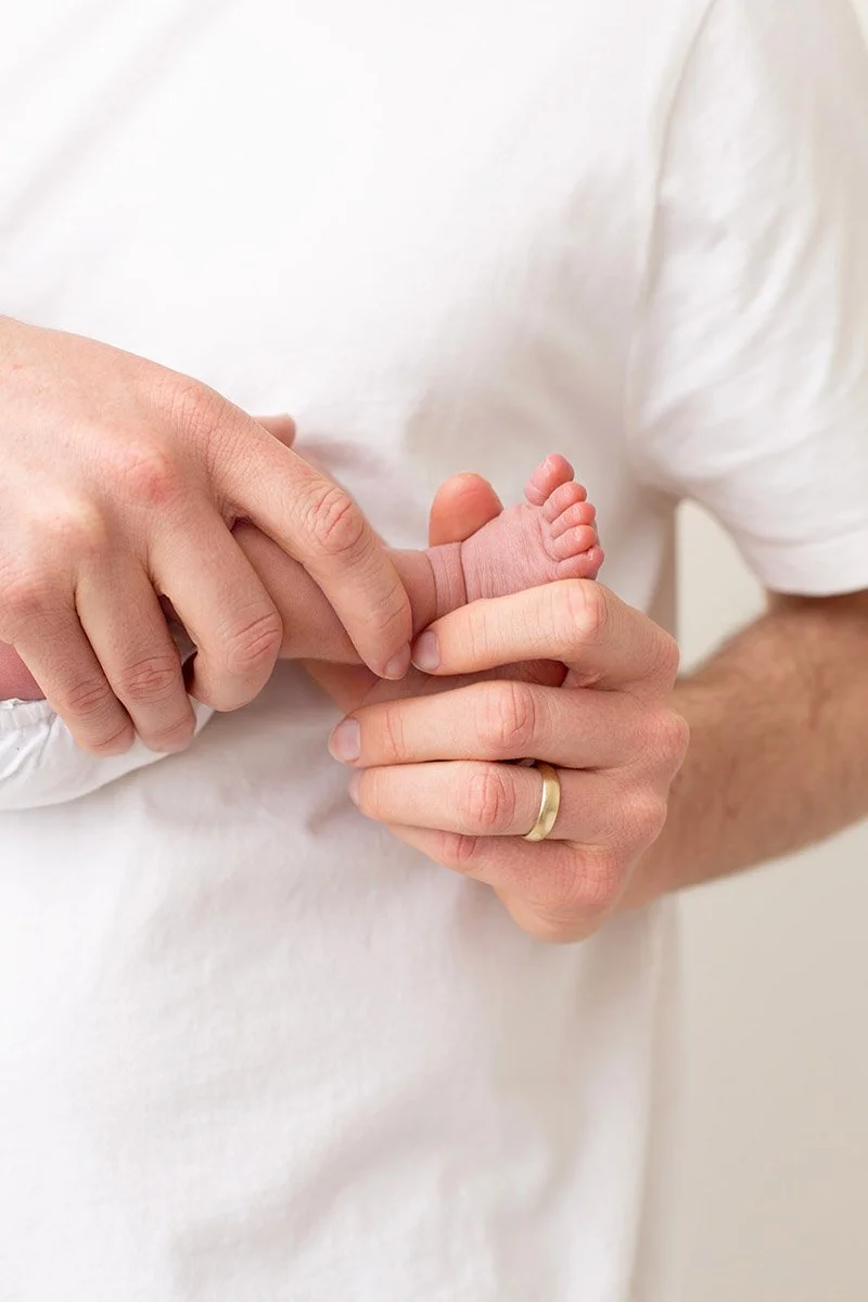 An adult is holding a newborn baby's foot in their hands.