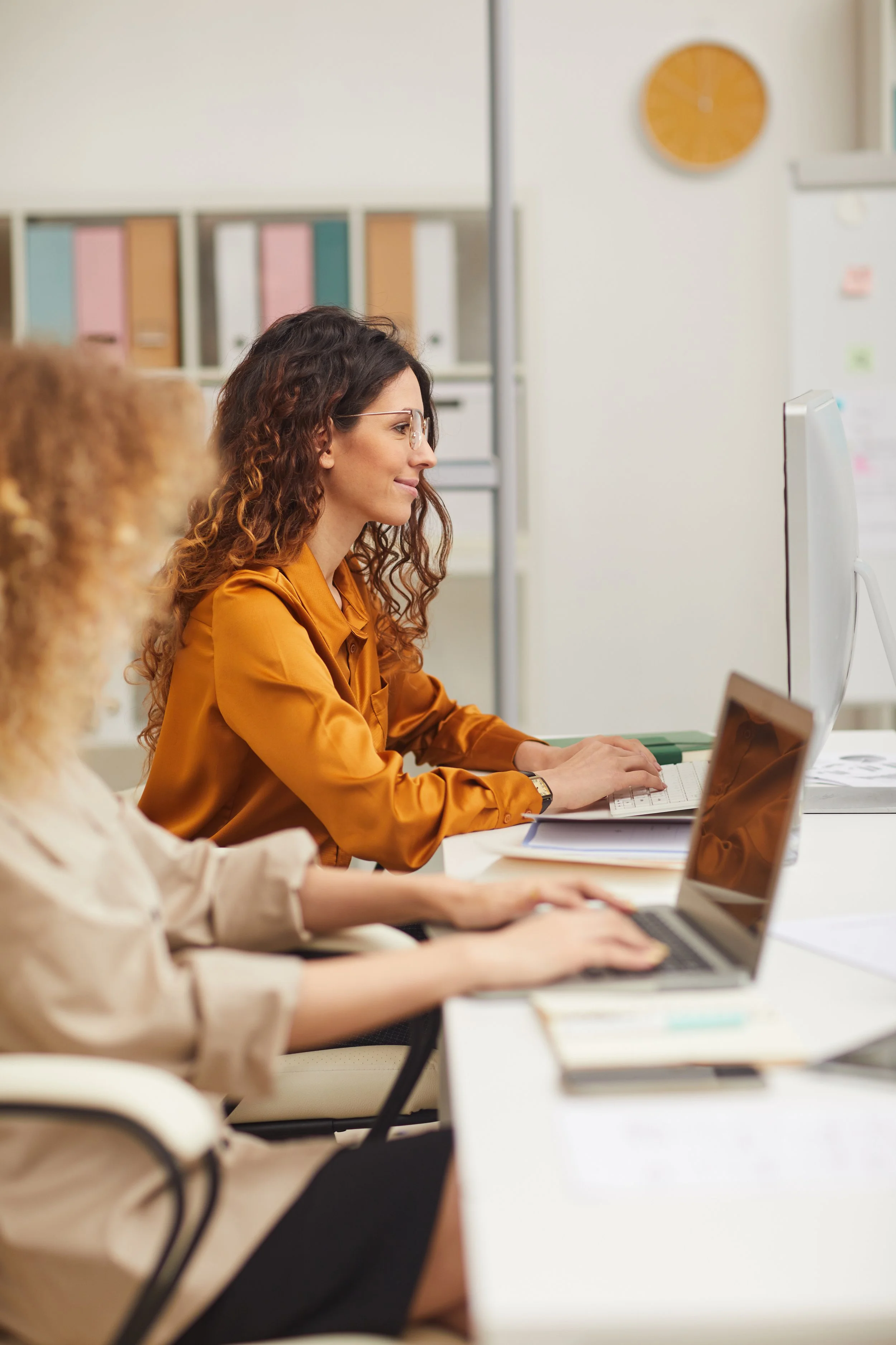 Two women sat at desk using laptops.