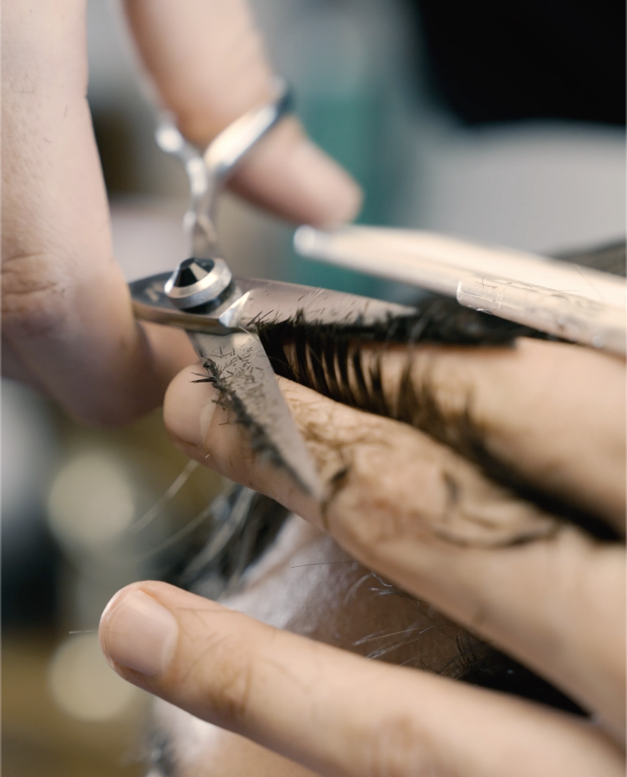 Close-up of a hairdresser cutting a person's hair with scissors.