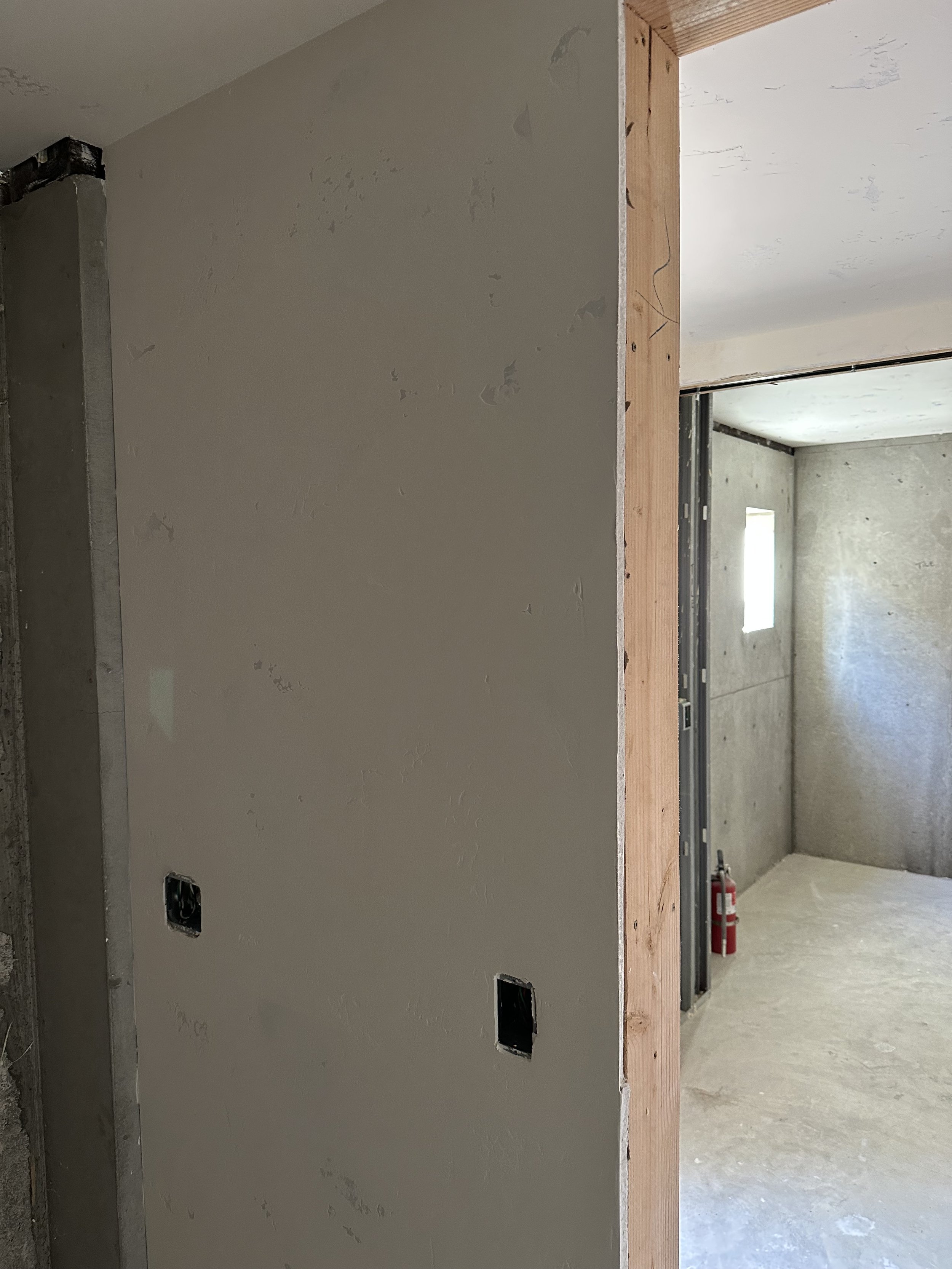  Rough-framing shot with a door opening — exposed wood studs on one side, taped drywall on the other. 