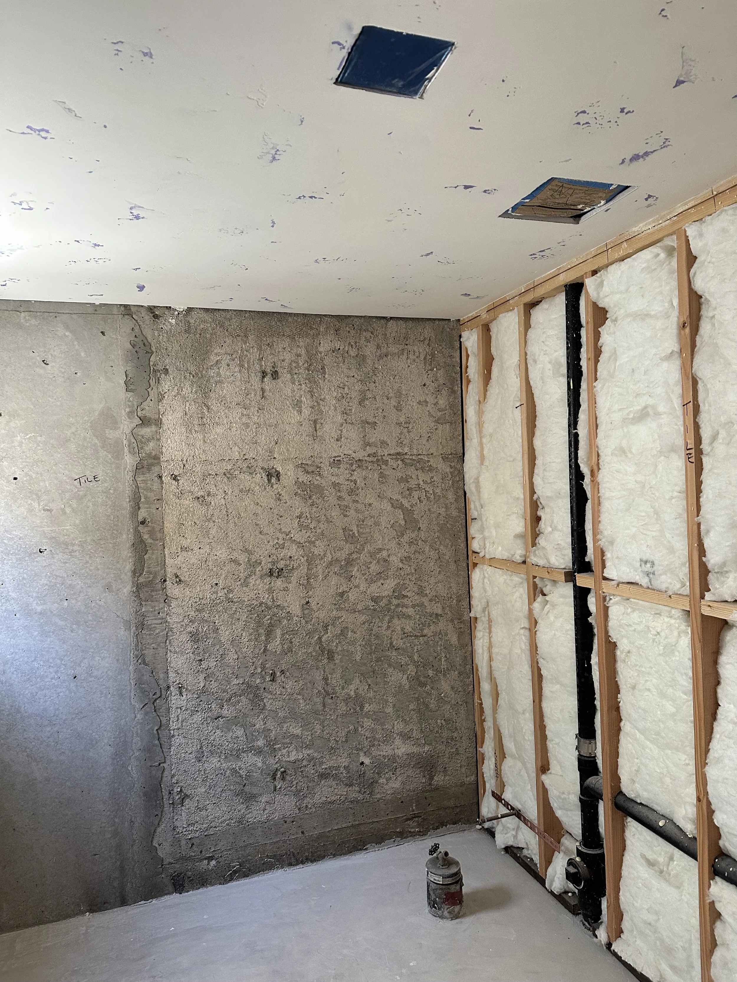  Exposed wood-stud wall/ceiling cavity with white spray-foam insulation and an electrical box. 