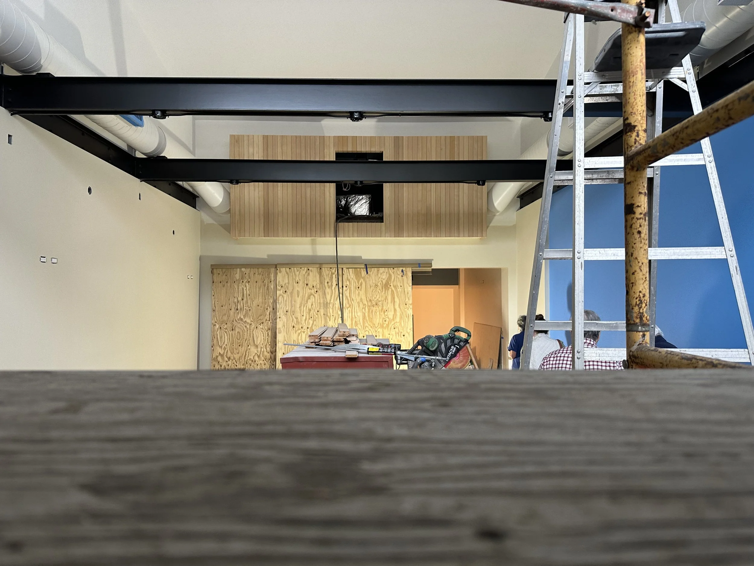  Wide interior shot showing the wood-slat “boxcar” enclosure from below, with Museum Staff talking near a workbench. 