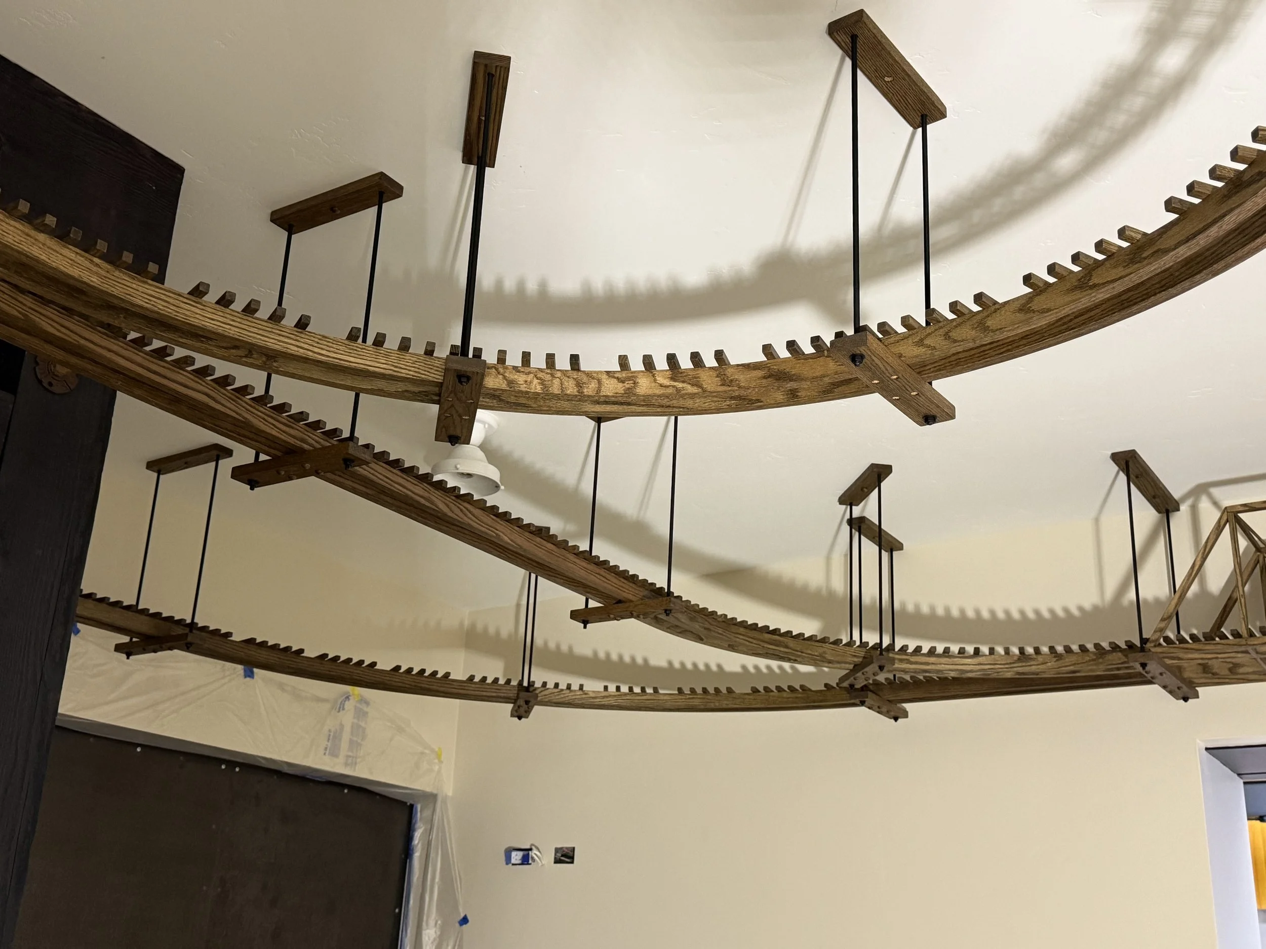  Similar wide view of the suspended curved track runs from a different angle, hanger rods and mounting blocks visible against the ceiling. 