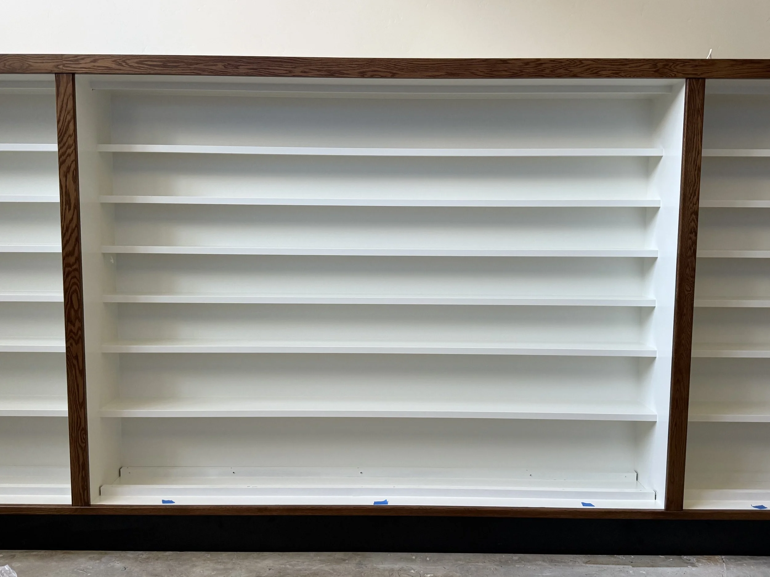  Close-up of one shelving bay, white-painted shelves in dark wood trim. 