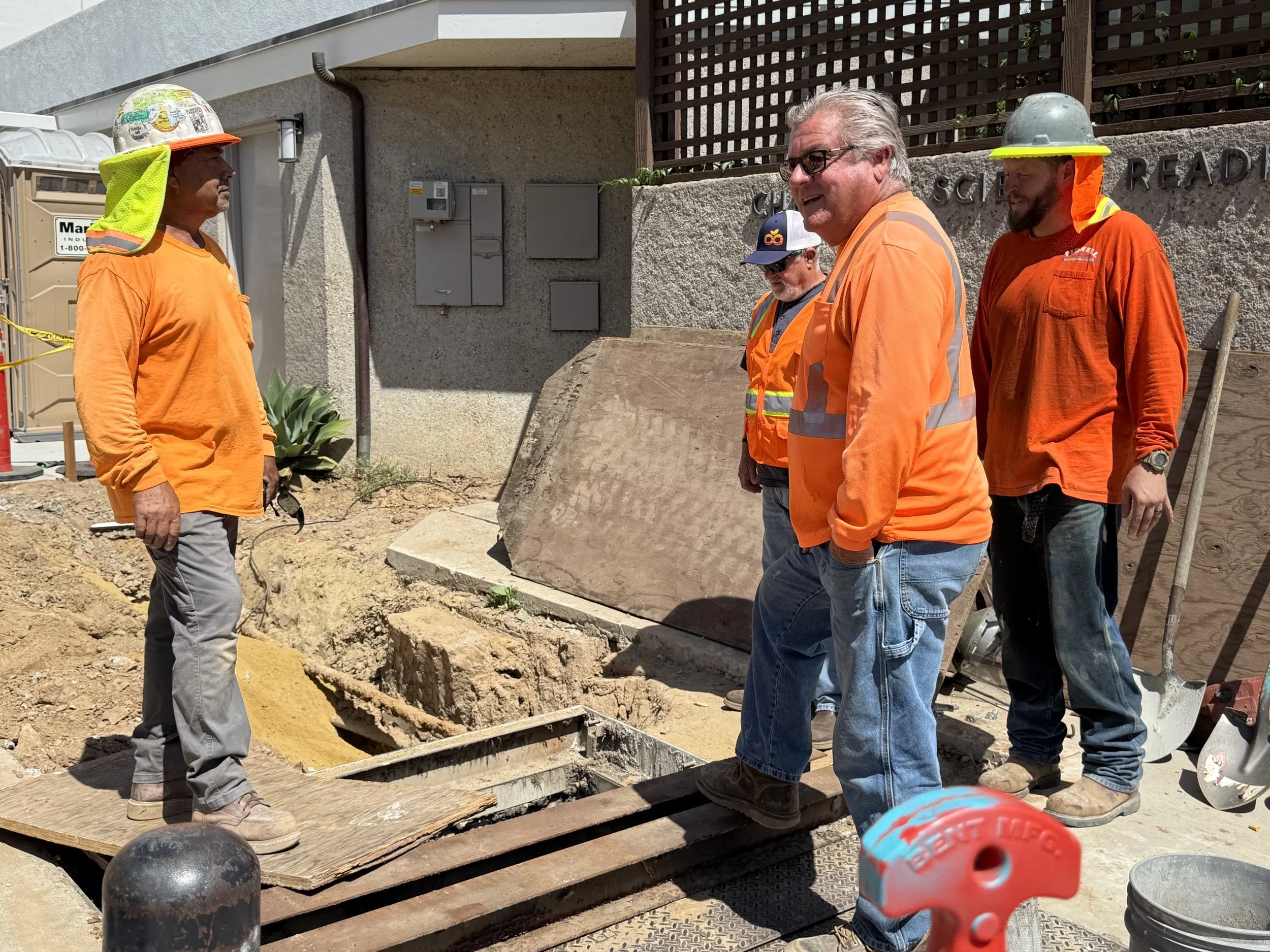  Group shot of the crew standing near the trench, mid-conversation. 